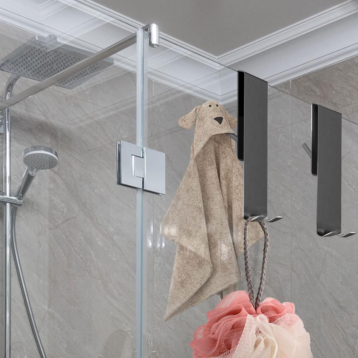 Eine Dusche mit Glastüren. Ein handtuchförmiger Hund hängt. Ein Schwamm und Haken sind sichtbar. Ein Duschkopf ist vorhanden.