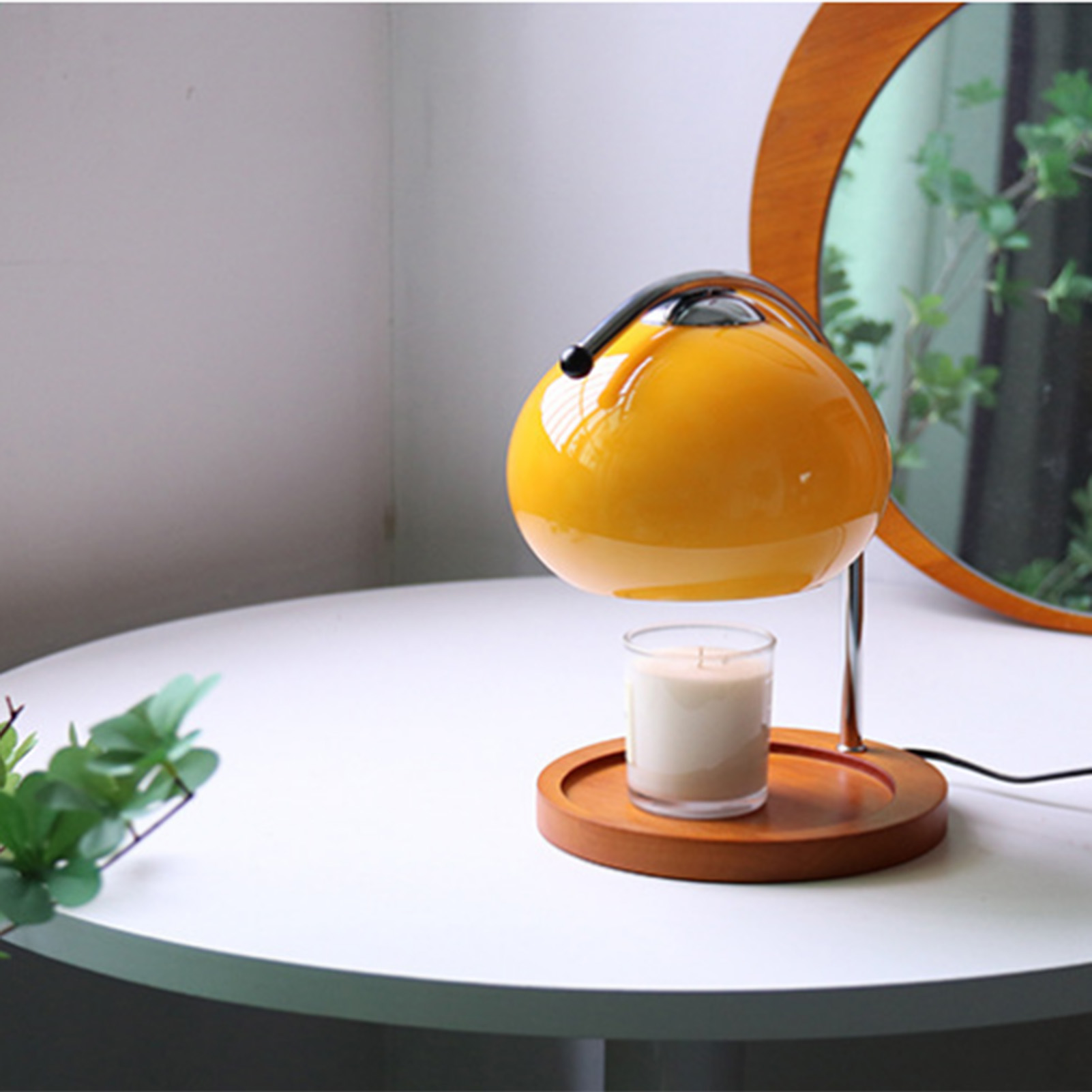 Eine gelbe Lampe mit einer Kerze auf einem Holzsockel steht auf einem weißen Tisch. Im Hintergrund ist ein Spiegel.