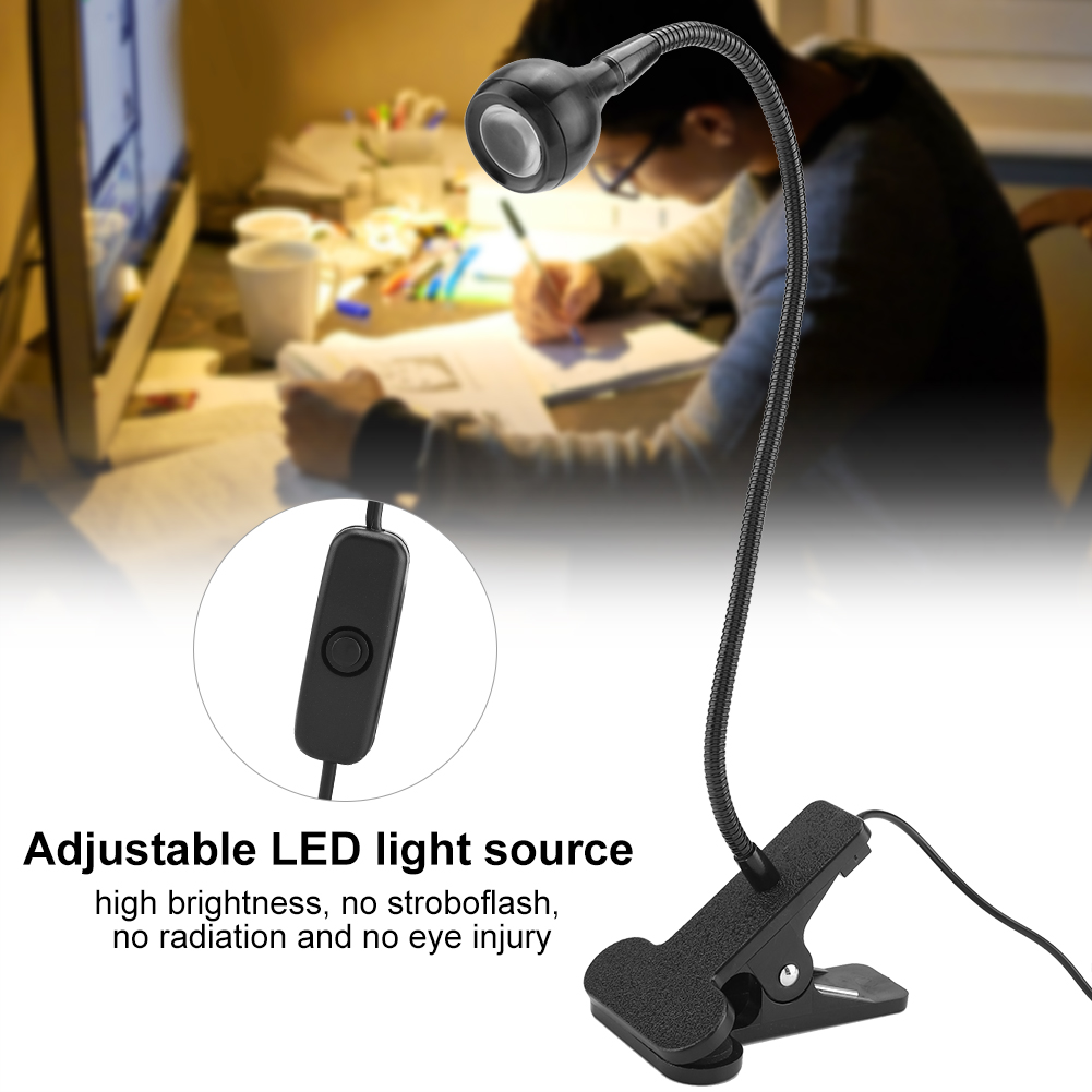 Eine schwarze, verstellbare LED-Schreibtischlampe leuchtet. Im Hintergrund schreibt eine Person an einem Schreibtisch. Die Lampe hat einen Clipfuß und Schalter.