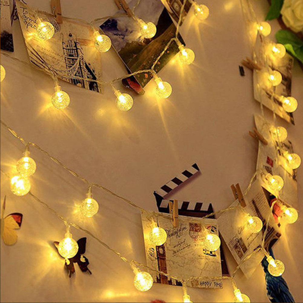 Lichterketten mit Kugelbirnen und Fotos, die an einer Wand befestigt sind. Die Lichter sind warmgelb. Schmetterlinge und eine Filmklappe sind vorhanden.