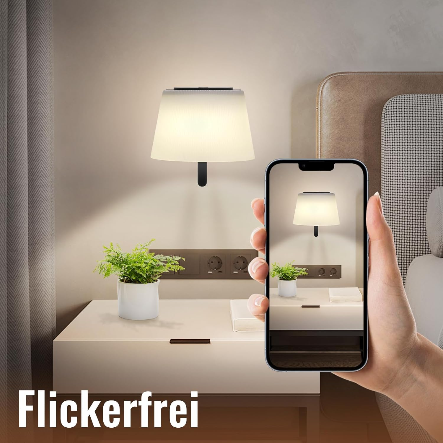 Una mano che tiene un telefono che mostra una lampada, un comodino con una pianta e una lampada da parete. La parola "Flickerfrei" è in basso.