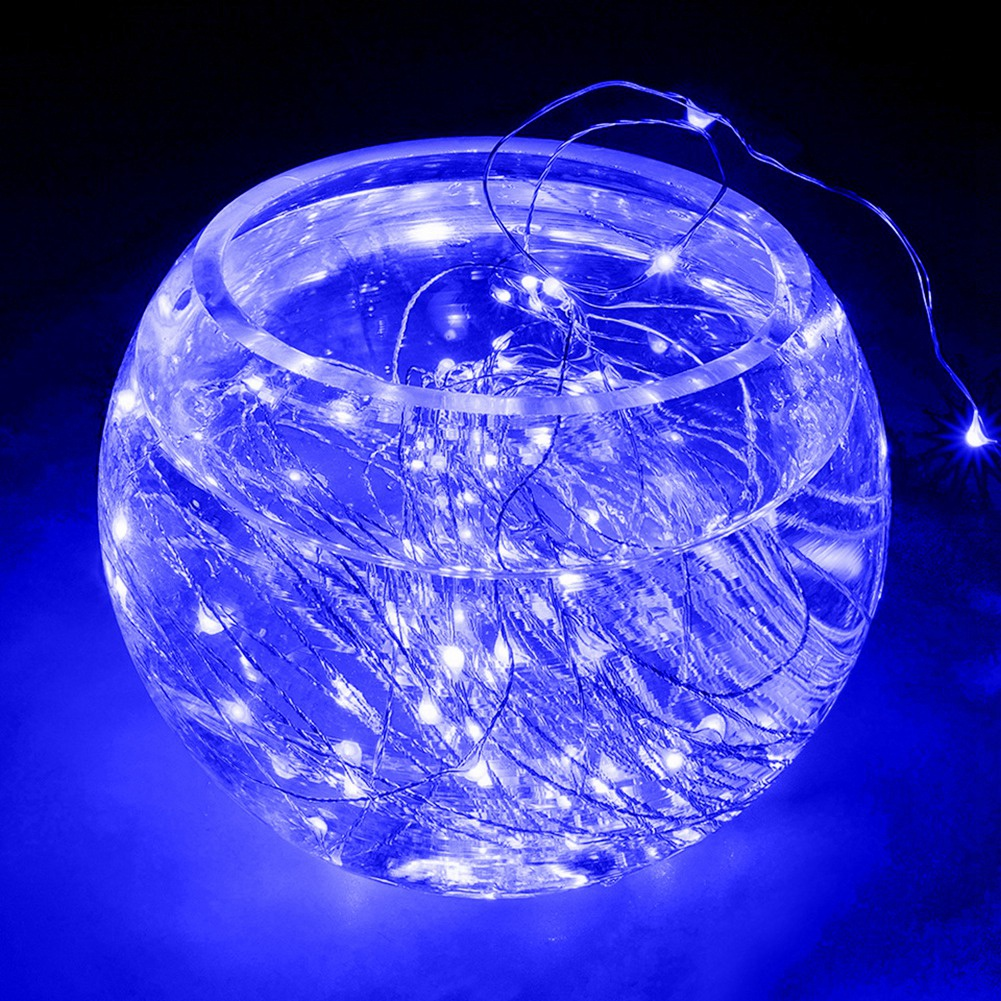 Eine Glasschale gefüllt mit Wasser und kleinen blauen Lichtern. Die Schale steht auf einer blauen Oberfläche mit schwarzem Hintergrund.