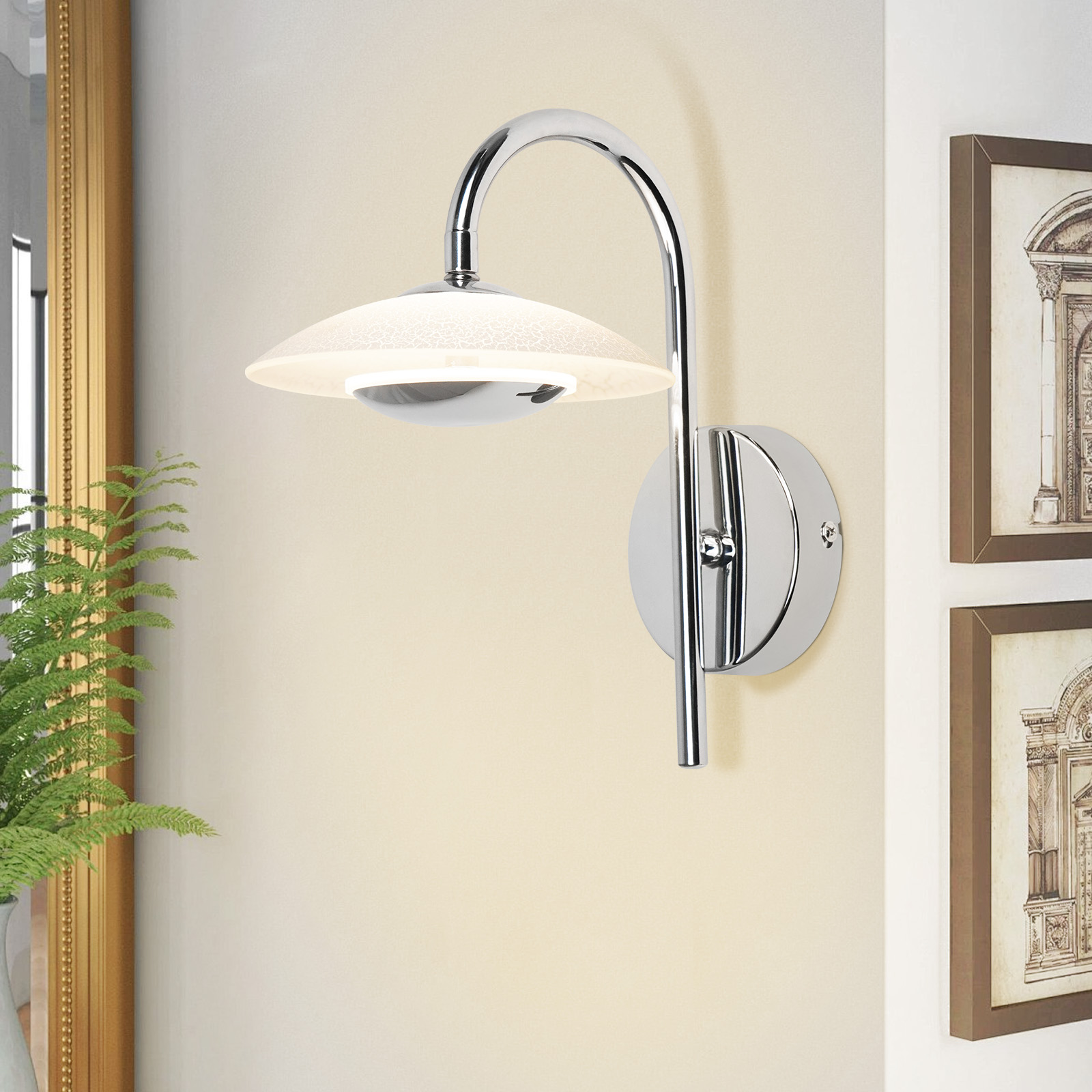 Un'applique da parete moderna con un braccio cromato curvo e un paralume in vetro smerigliato, montata su una parete beige chiaro.