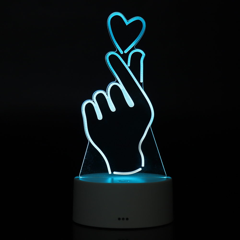 Eine leuchtende Handgestenlampe bildet mit den Fingern ein Herz. Sie hat einen weißen Sockel und strahlt blaues Licht aus, vor schwarzem Hintergrund.