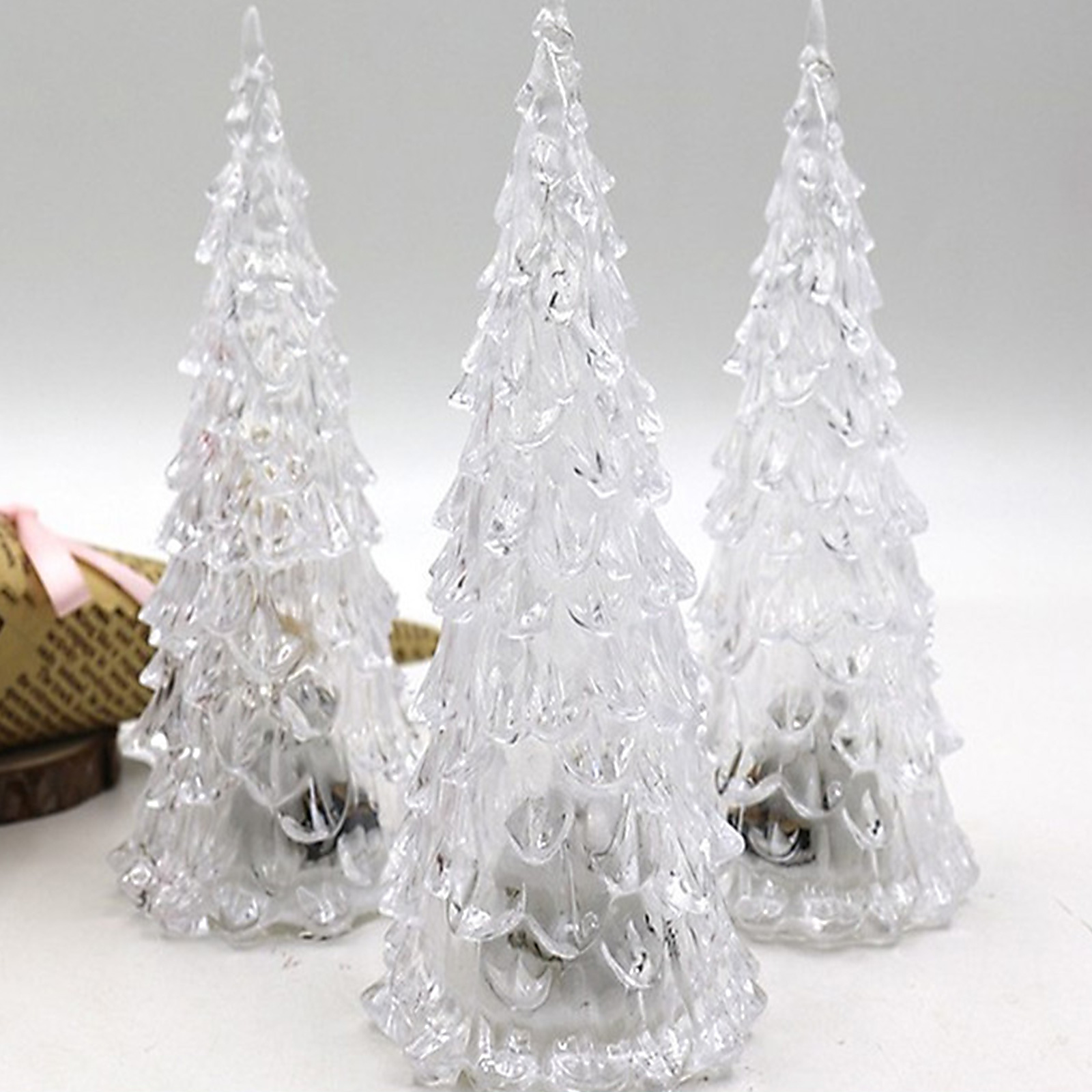 Drei transparente, dekorative Weihnachtsbäume werden vor einem schlichten weißen Hintergrund ausgestellt.