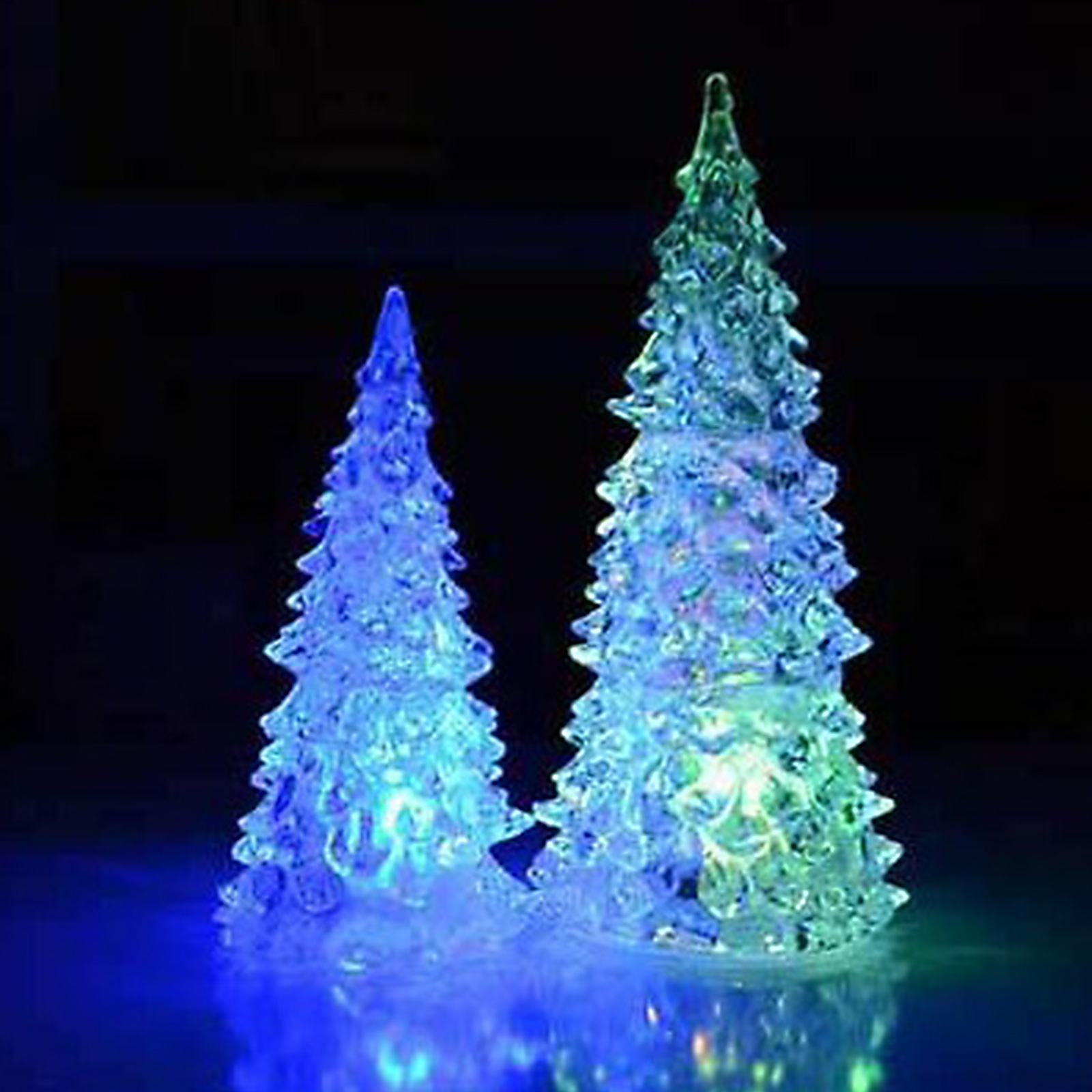 Zwei beleuchtete, transparente Weihnachtsbäume mit blauen und grünen Farbtönen vor dunklem Hintergrund.