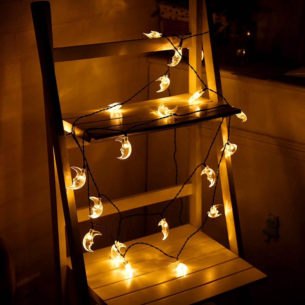 Eine Holzleiter mit mondförmigen Lichterketten. Die Lichter leuchten gelb und erzeugen eine warme, gemütliche Atmosphäre.
