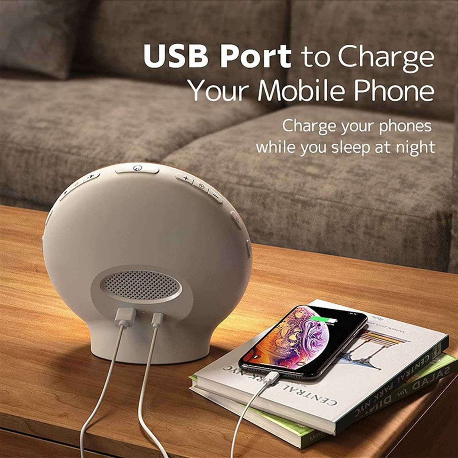 Eine weiße Uhr mit USB-Anschlüssen lädt ein Telefon auf Büchern auf. Im Hintergrund ist eine Couch.
