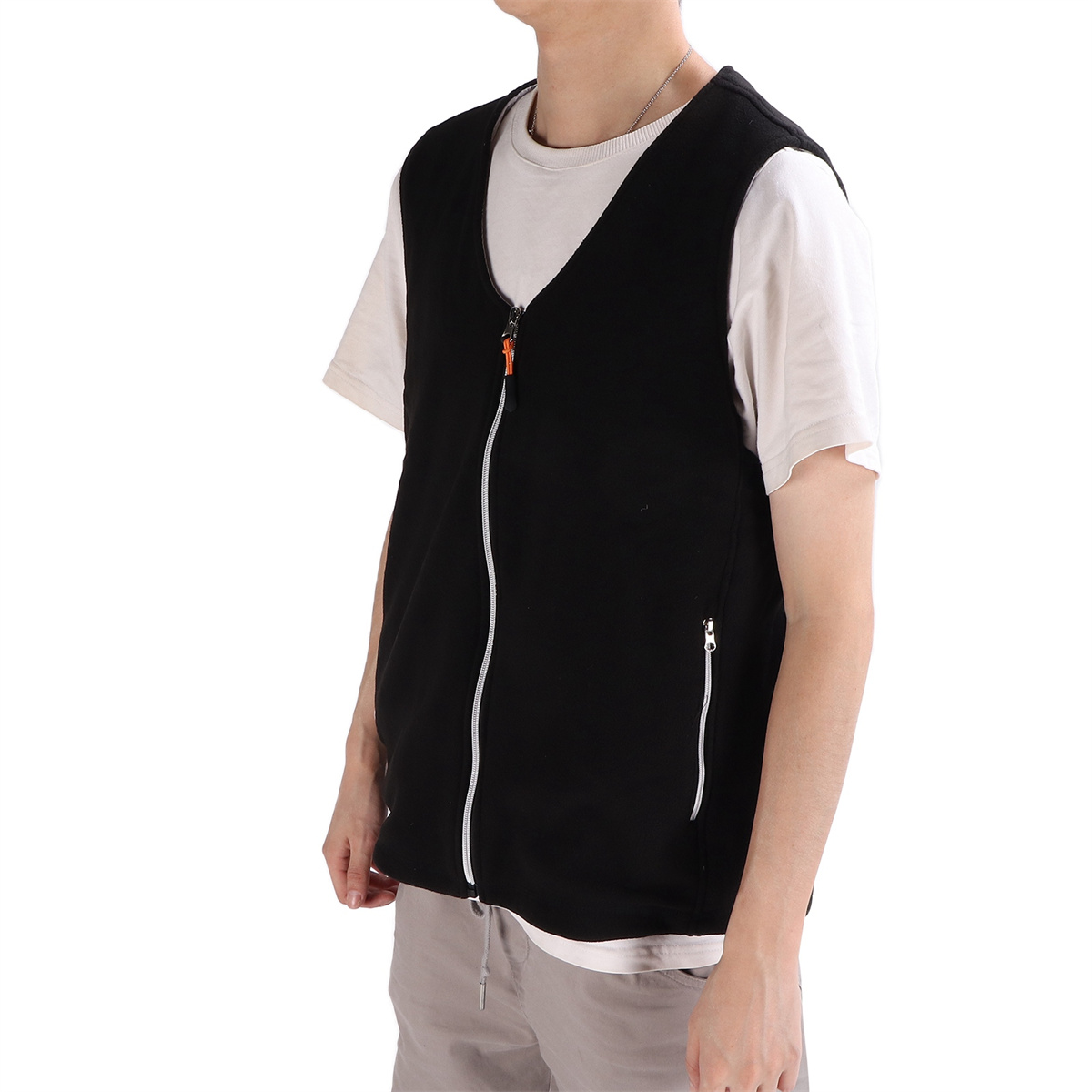 Eine Person trägt eine schwarze Weste über einem weißen T-Shirt. Die Weste hat einen weißen Reißverschluss und eine kleine Seitentasche.