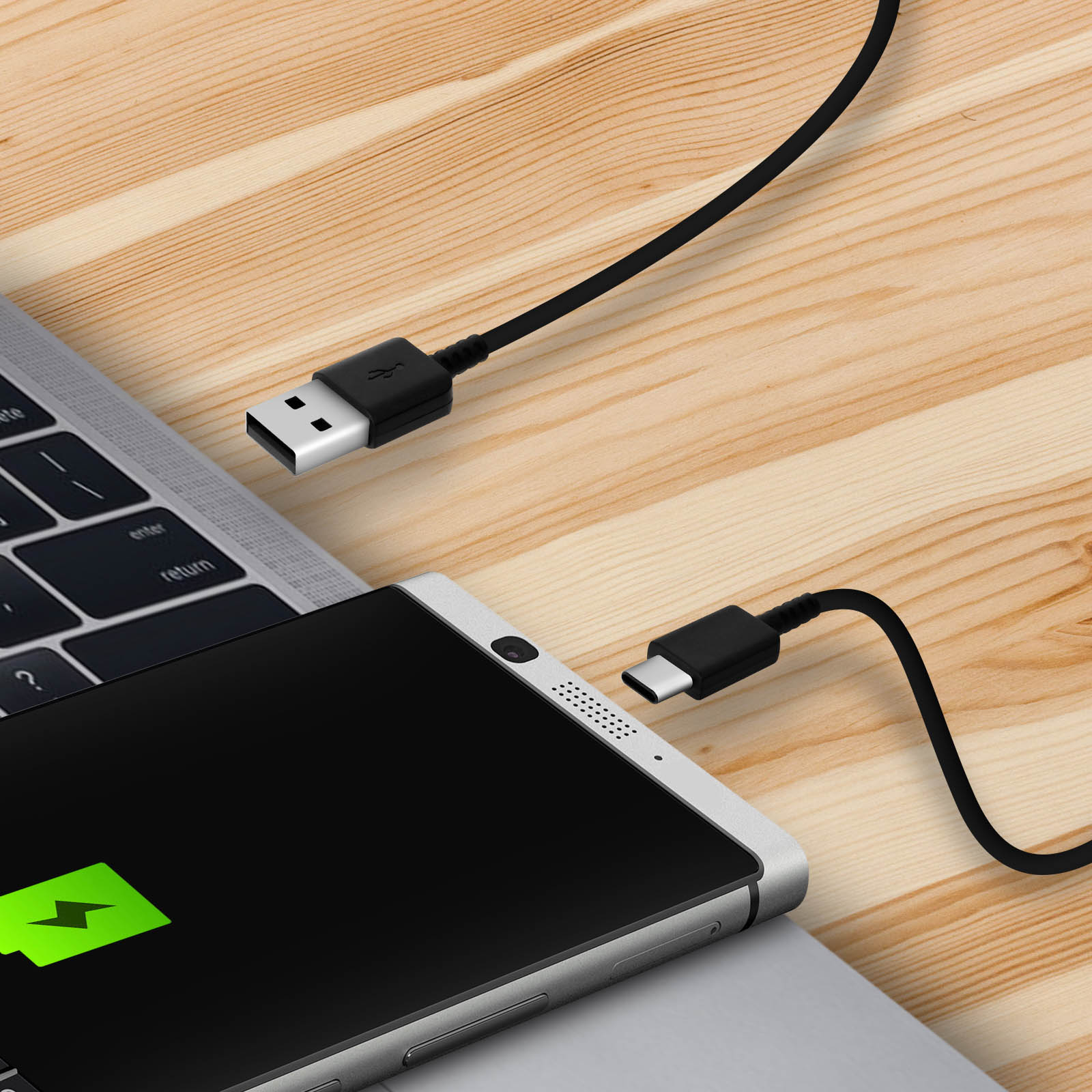 Telefono in carica su un laptop. Un cavo USB nero collega il telefono e il laptop. Il telefono mostra un simbolo di ricarica.