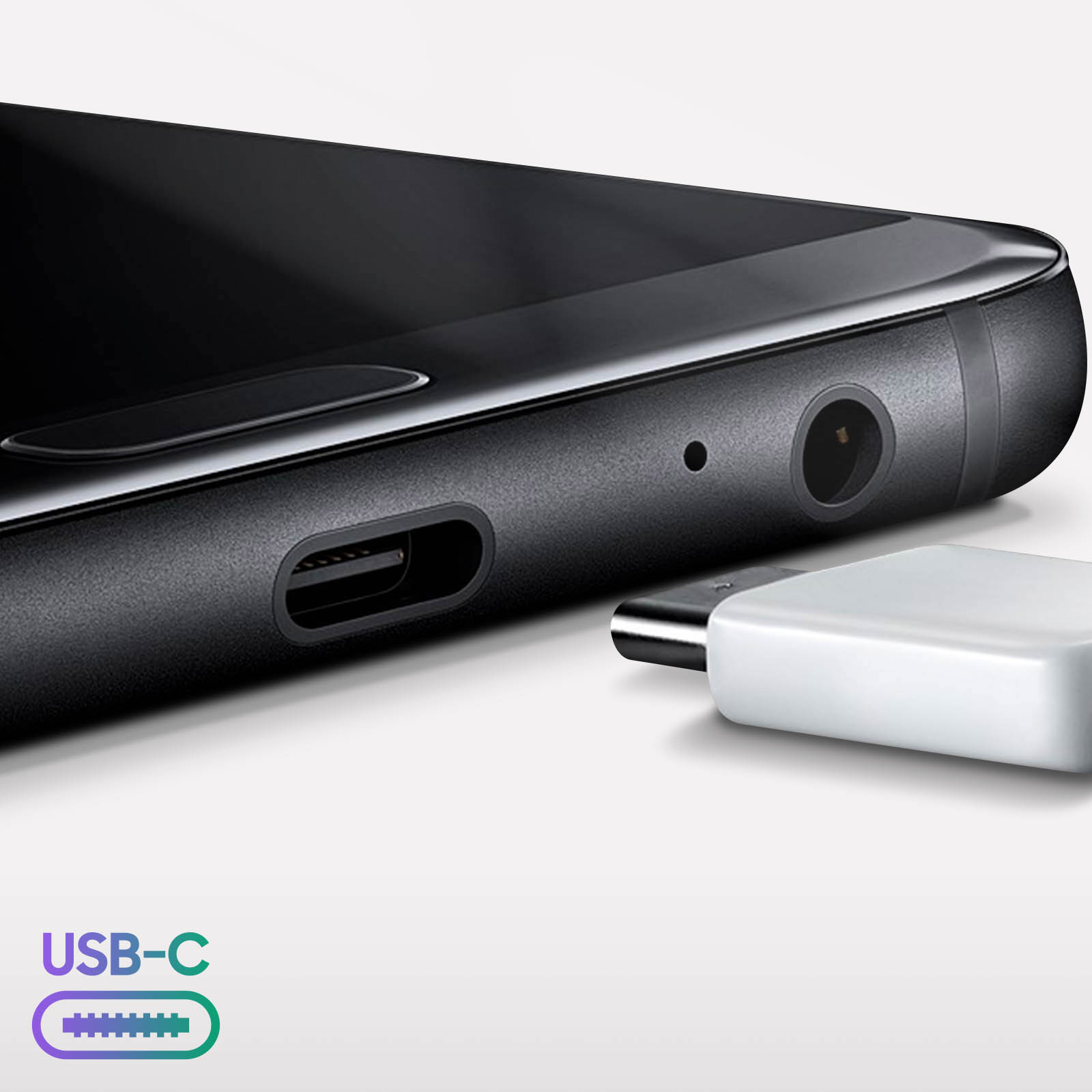 Primo piano di telefono nero con porta USB-C, jack per cuffie e adattatore bianco. Logo USB-C visibile.