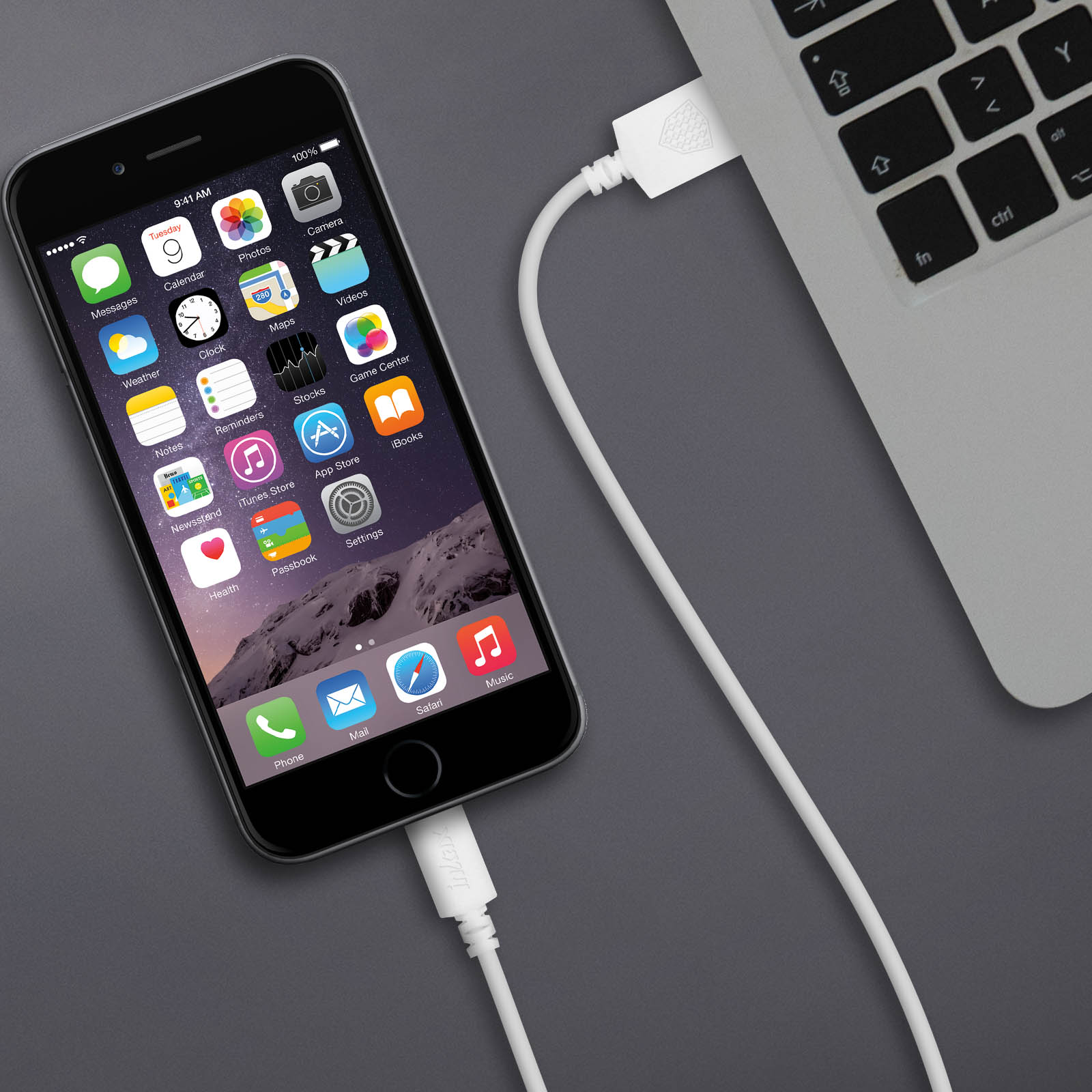 Un iPhone est connecté à un ordinateur portable via un câble de chargement blanc. L'écran affiche des icônes.