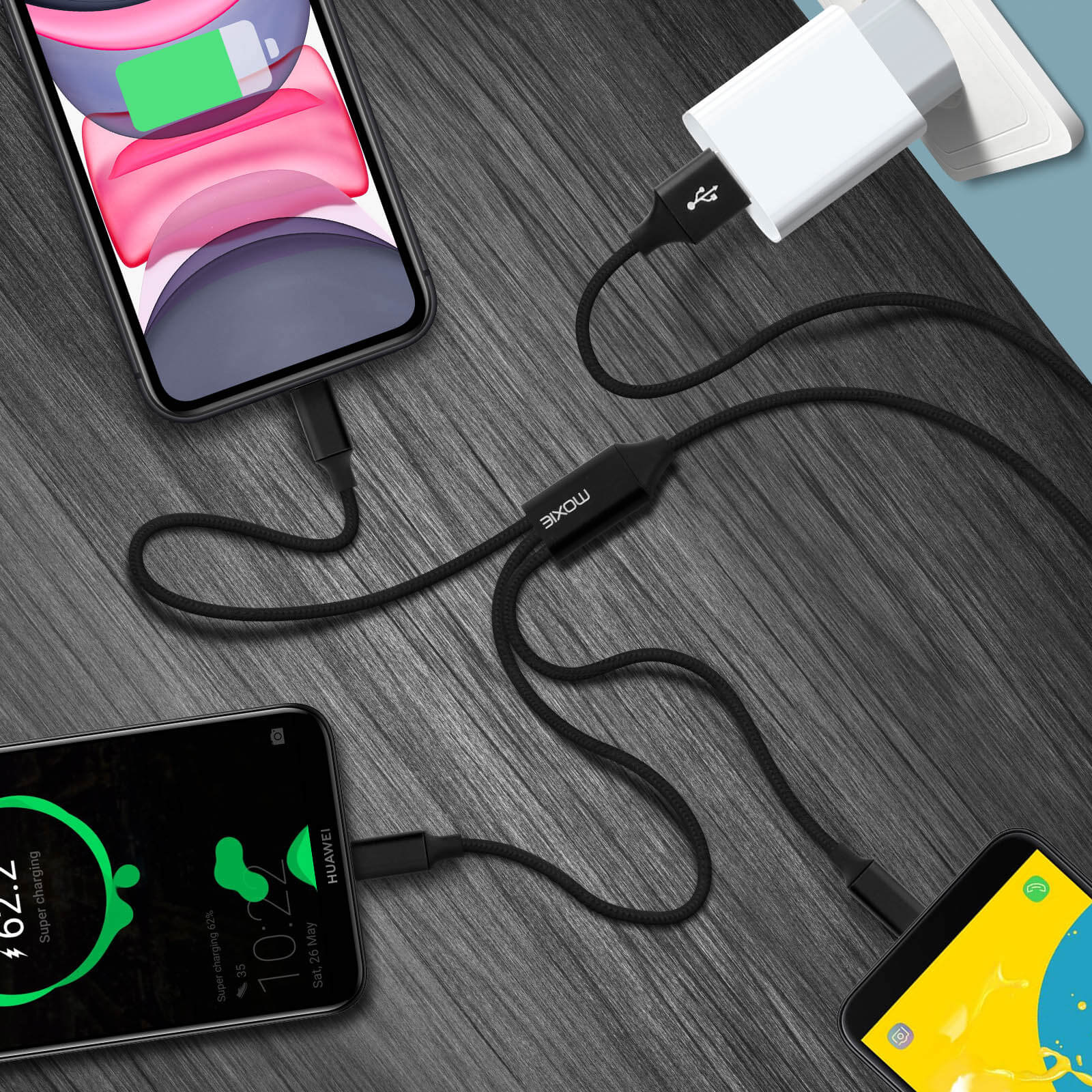 Tre smartphone in carica con cavi neri. Un caricatore bianco è collegato a una presa. Lo sfondo è una superficie in legno.