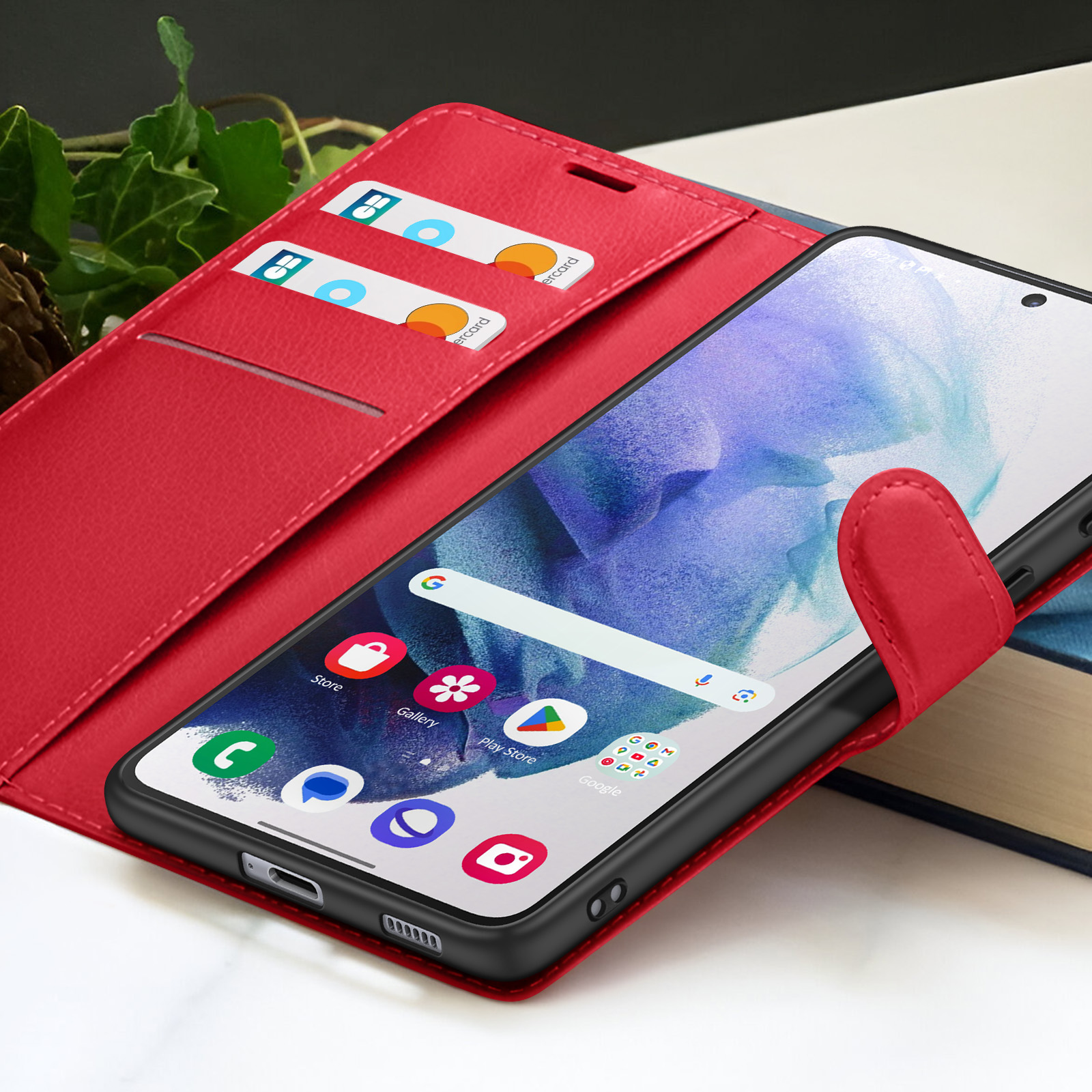 Étui de téléphone rouge avec un téléphone affichant des icônes d'applications, des cartes de crédit dans l'étui et un livre en arrière-plan.