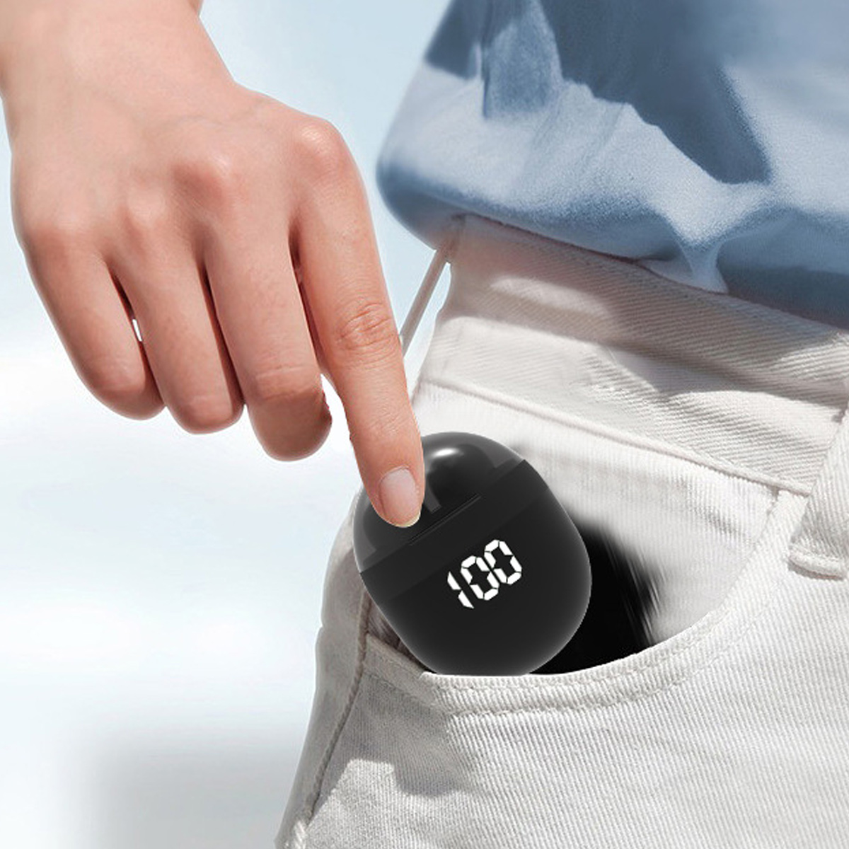 Eine Person legt eine schwarze Ladehülle mit digitaler Anzeige in eine Tasche. Die Anzeige zeigt 100.
