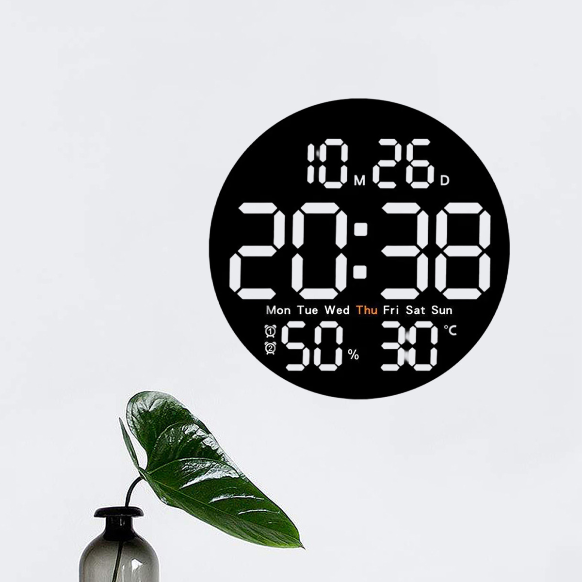 Eine schwarze Digitaluhr zeigt die Zeit 20:38, das Datum und Wetterdetails an. Eine Pflanze in einer Vase ist im Vordergrund.