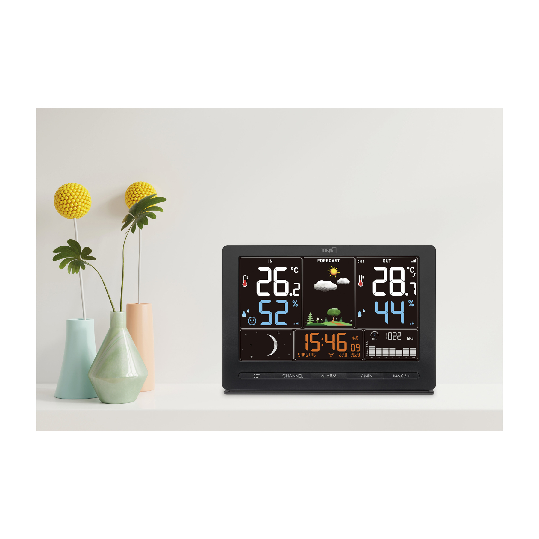 Eine Wetterstation mit Anzeige von Temperatur und Luftfeuchtigkeit, mit Blumen in Vasen.