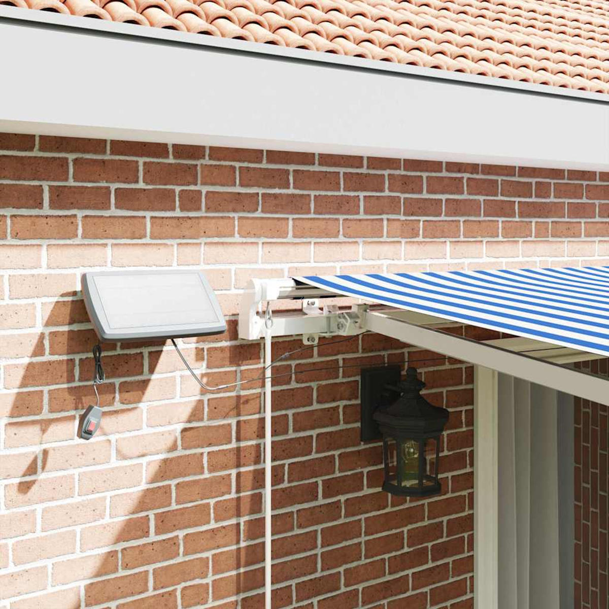 Eine Backsteinmauer mit einer Markise mit blau-weißen Streifen. Ein Solarpanel und eine Lampe sind an der Wand befestigt.