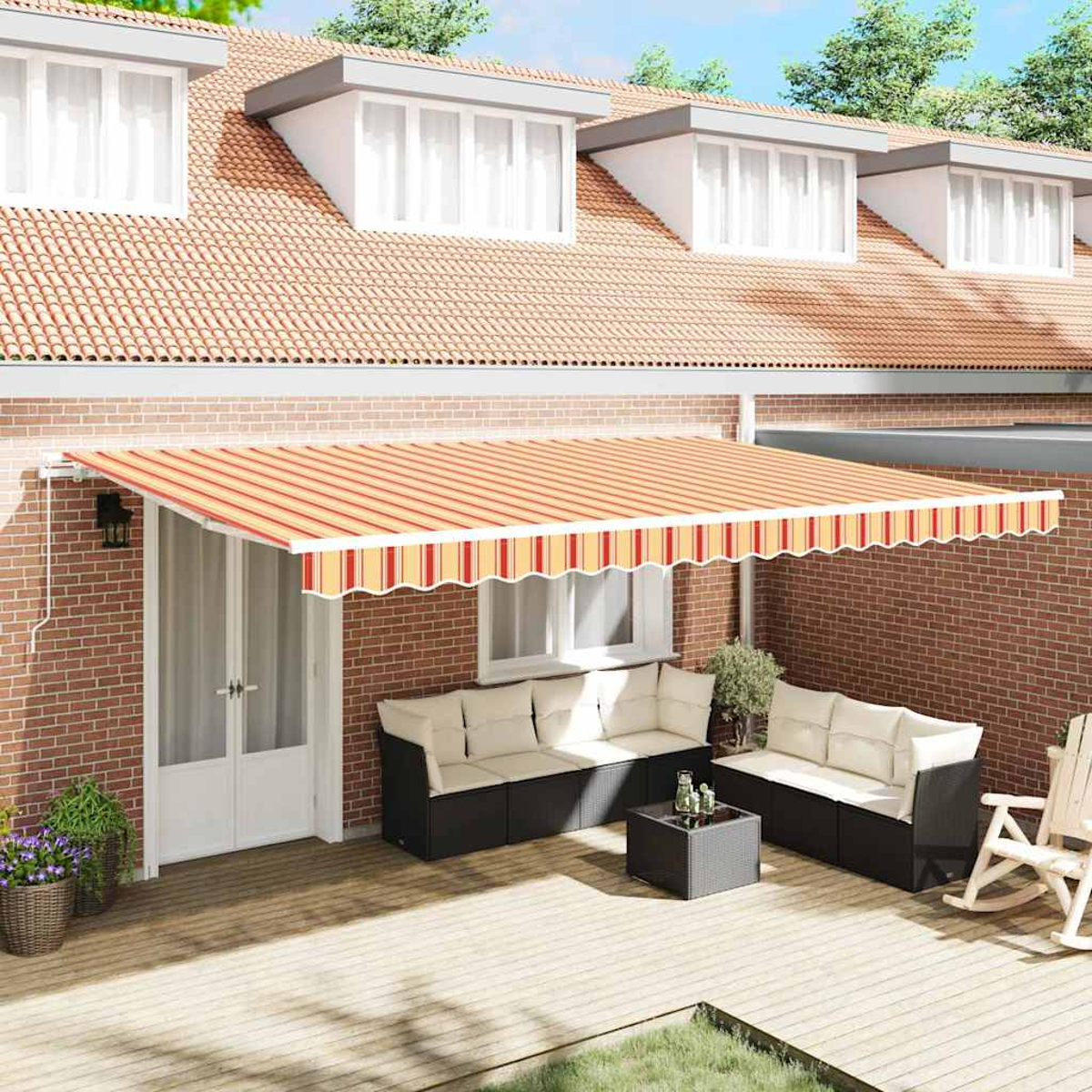 Eine Terrasse mit gestreifter Markise, Sitzgelegenheiten und einer Backsteinmauer. Im Hintergrund ein Haus mit Dachgauben.