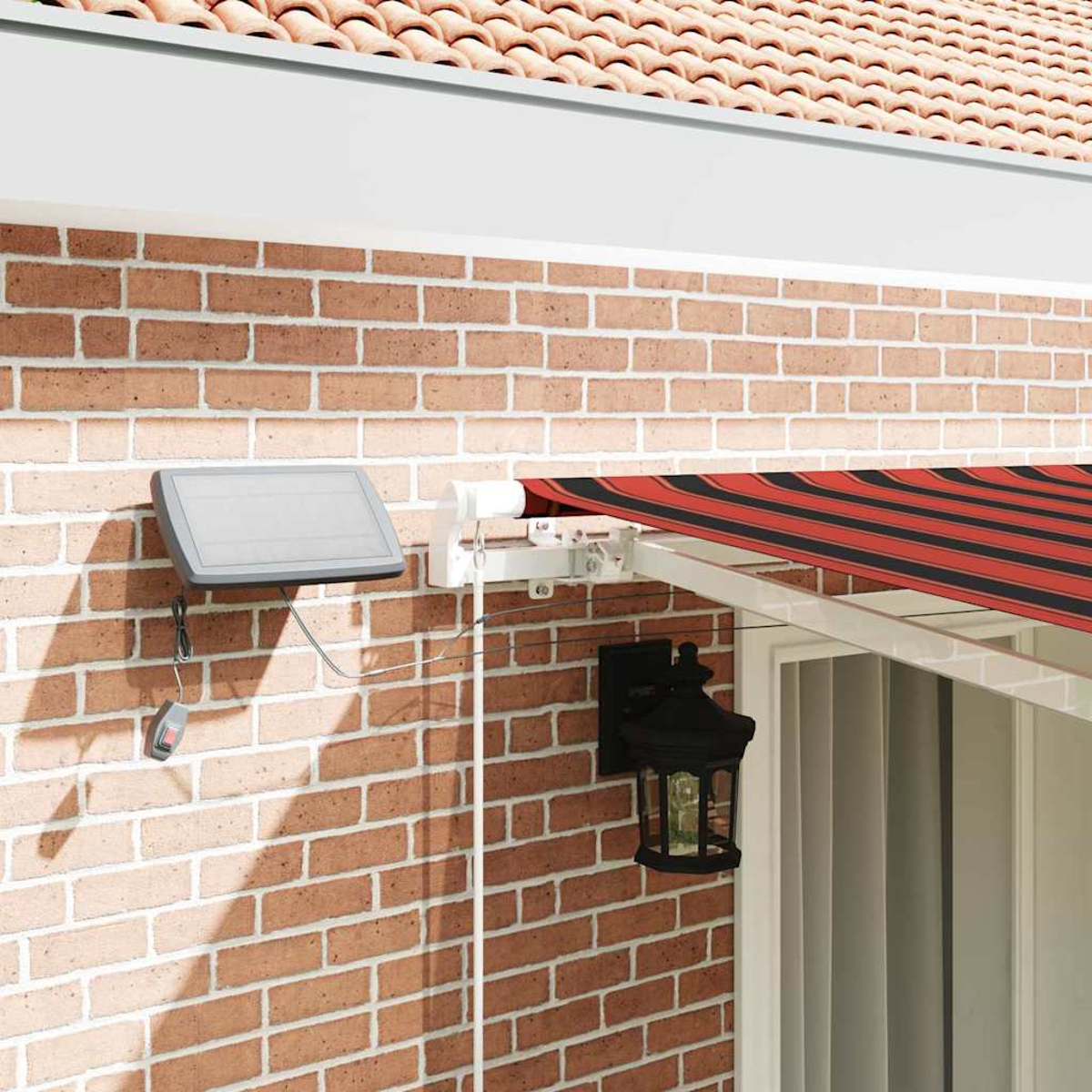 Eine Backsteinmauer mit Solarpanel, rot-schwarz gestreifter Markise und schwarzer Laterne. Ein Dach ist sichtbar.