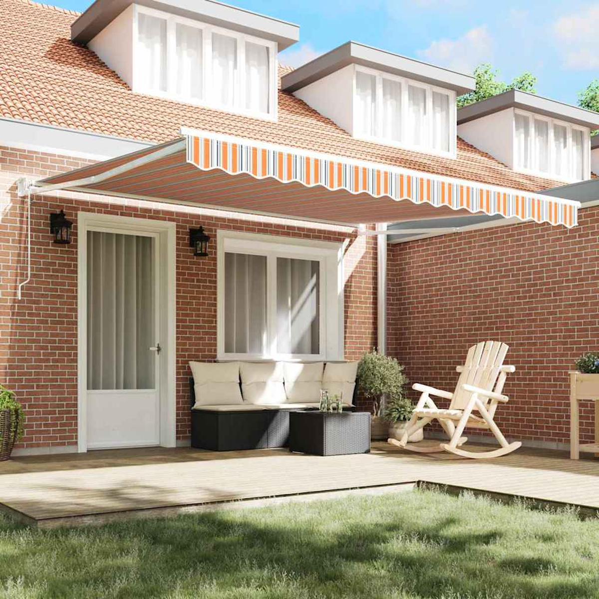 Ein Haus mit Terrasse, gestreifter Markise, Sitzgelegenheiten und Schaukelstuhl. Eine Ziegelmauer und Rasen sind sichtbar.