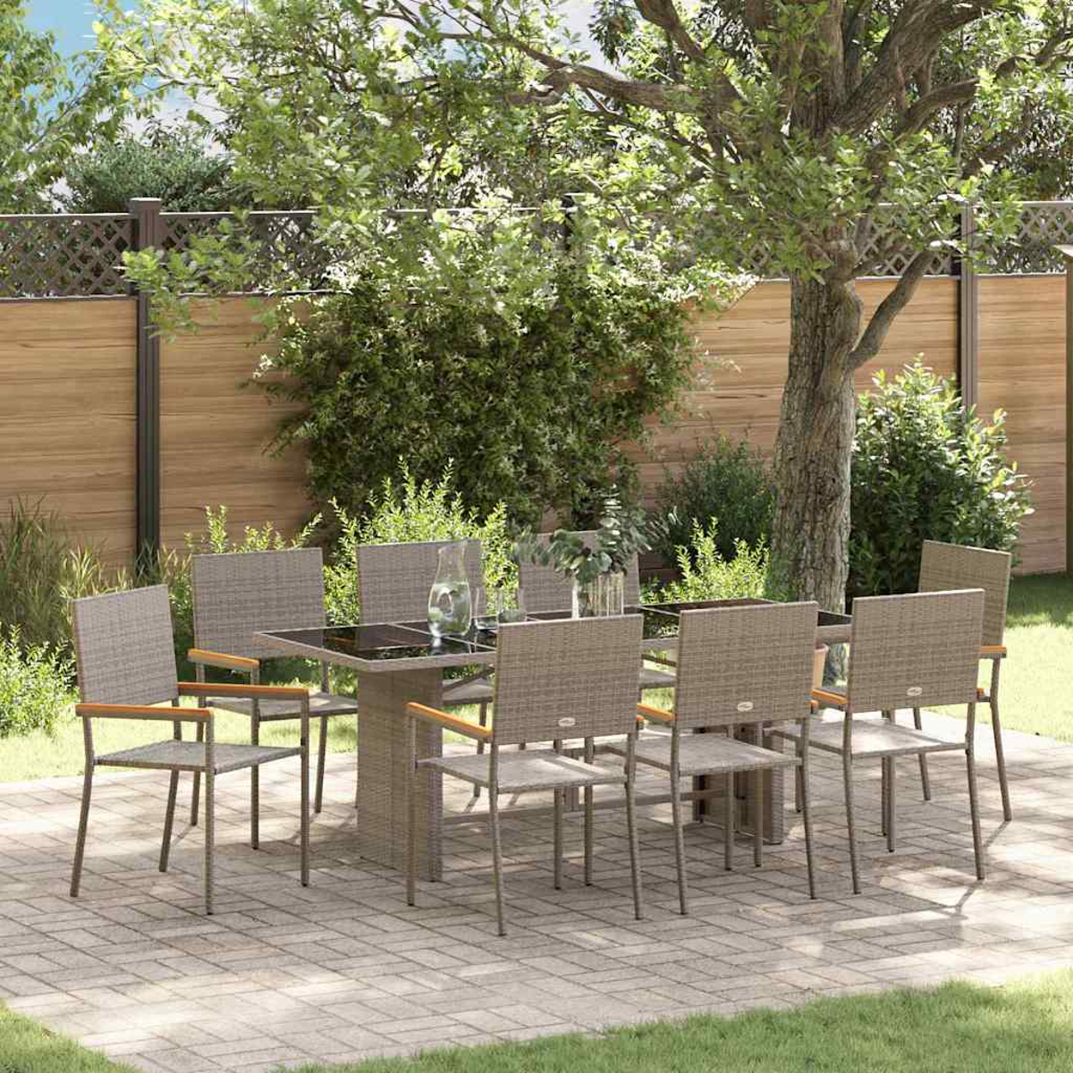 Essgruppe im Freien. Quadratischer Tisch, acht Stühle mit Holzarmlehnen, auf einer Terrasse. Bäume und Zaun im Hintergrund.