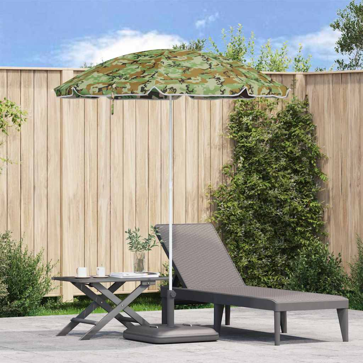 Una scena di patio con un ombrello mimetico, una sedia a sdraio e un tavolino con bevande. Una staccionata di legno sullo sfondo.