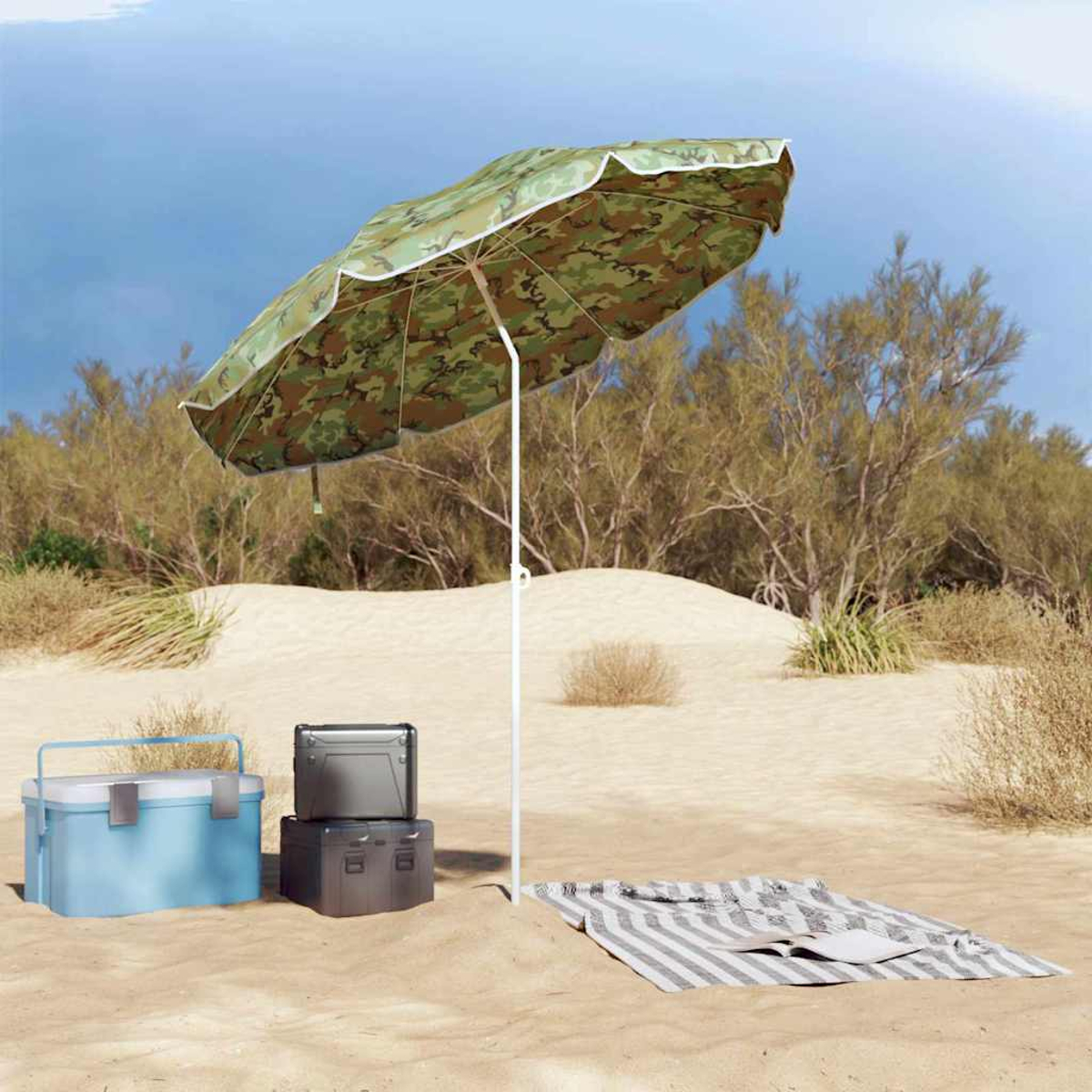 Una scena sulla spiaggia con un ombrellone mimetico, borse frigo e una coperta sulla sabbia. Alberi e cielo blu sullo sfondo.