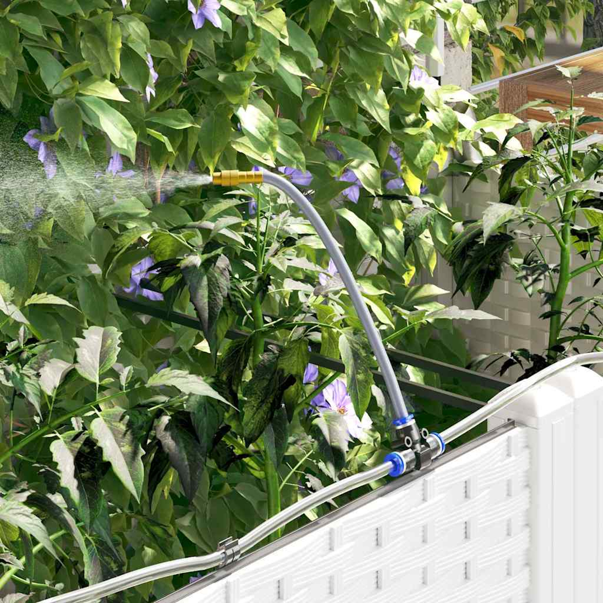 Ein Sprinkler, der Pflanzen bewässert. Grüne Blätter und lila Blumen im Hintergrund. Weißer Zaun im Vordergrund.