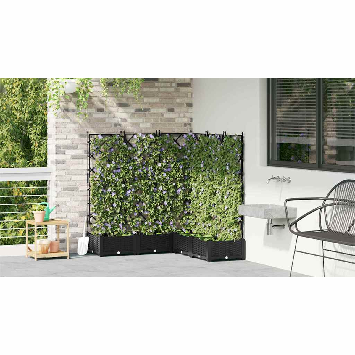 Eine Terrasse mit Kletterpflanzen an einem Spalier, einem schwarzen Stuhl und einem Waschbecken. Grüne Pflanzen und lila Blüten sind sichtbar.