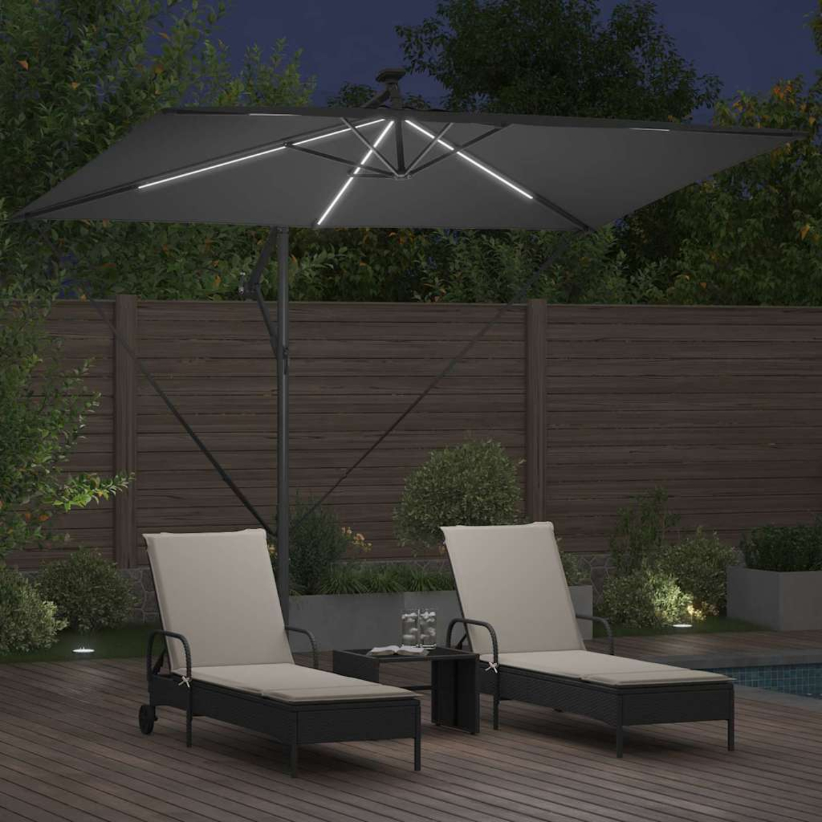 Scena notturna con mobili da patio. Due sedie a sdraio sotto un ombrellone illuminato. Tavolino con bicchieri. Deck e recinzione in legno.