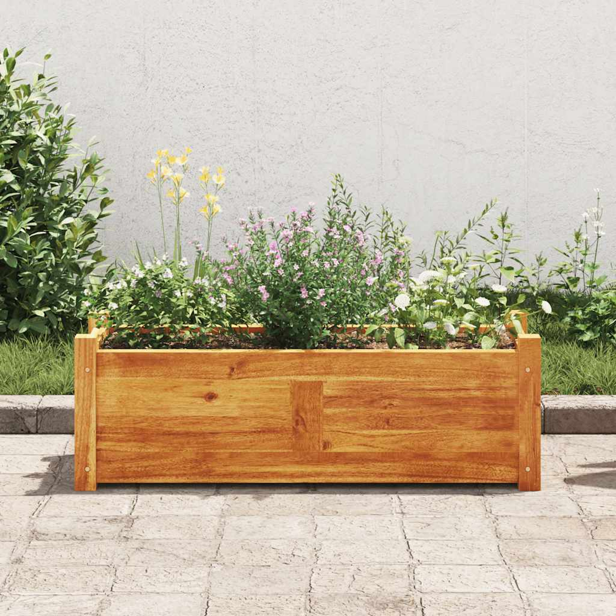 Eine Holzkasten mit Blumen und Pflanzen. Die Kiste steht auf einer Steinoberfläche, im Hintergrund eine weiße Wand.