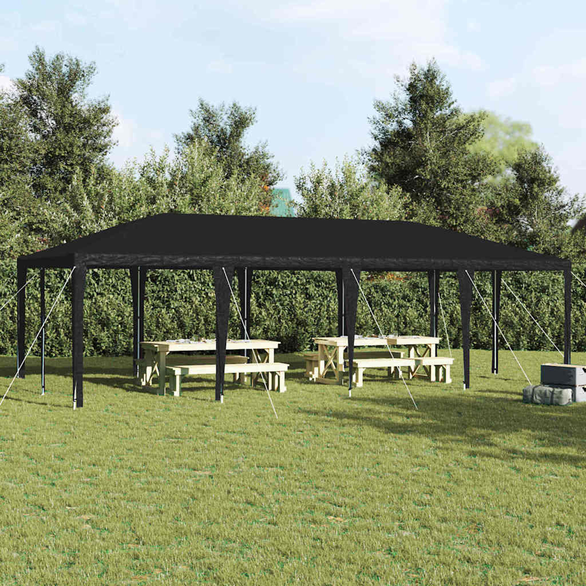 Una tenda nera su un'area erbosa. Tavoli da picnic all'interno. Alberi e cespugli sullo sfondo sotto un cielo soleggiato.