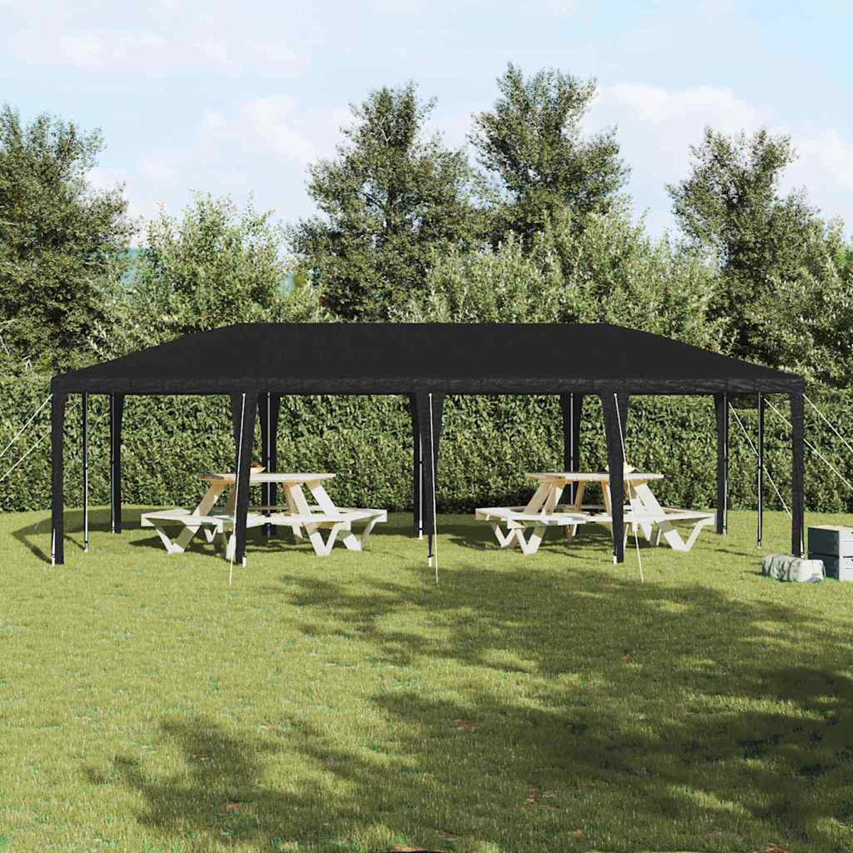 Un baldacchino nero sopra due tavoli da picnic su un prato verde. Gli alberi fanno da sfondo.