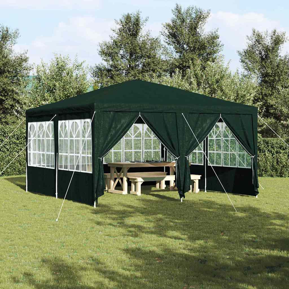 Un gazebo verde scuro con finestre con cornice bianca si trova sull'erba. All'interno, un tavolo da picnic in legno. Alberi sullo sfondo.