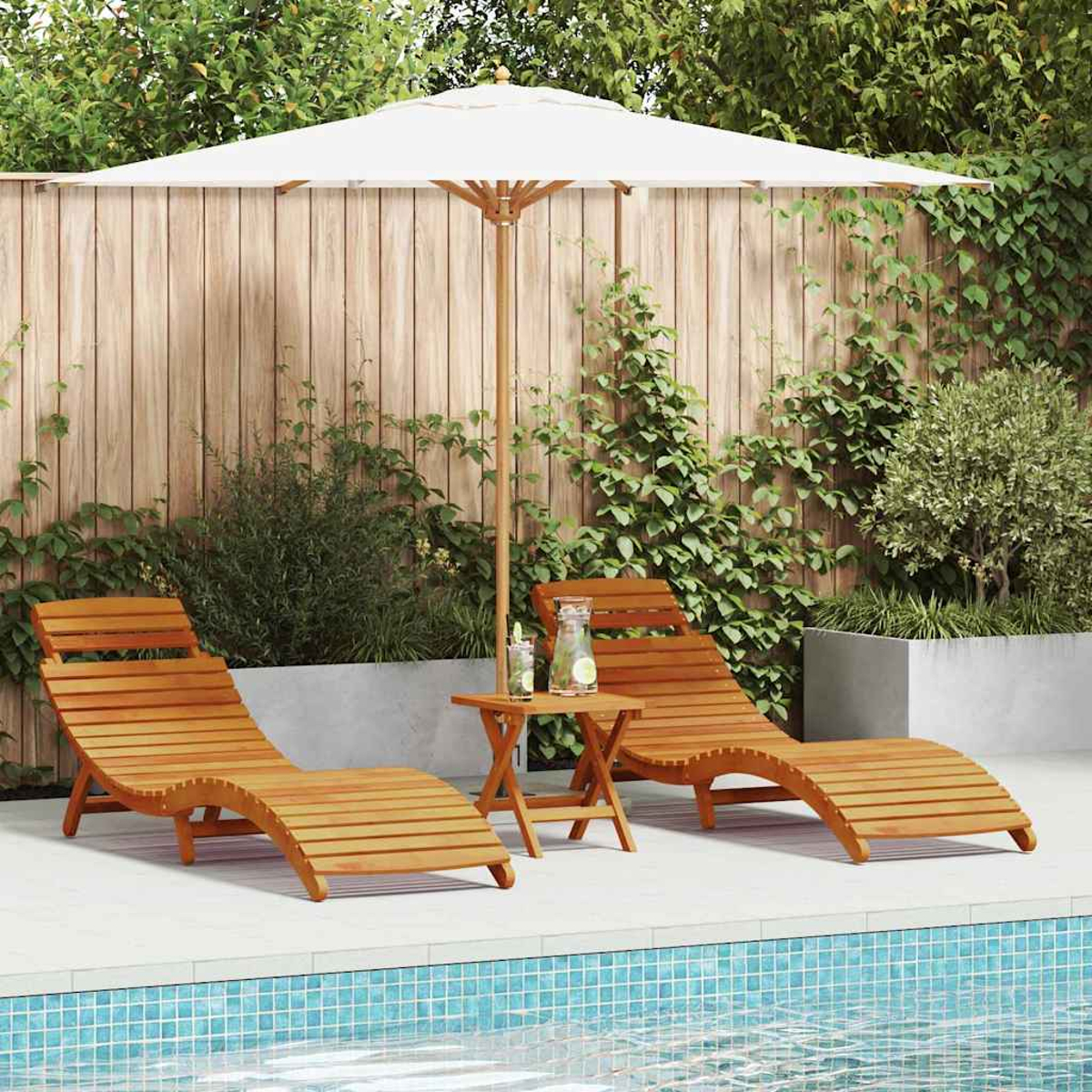 Zwei Holzliegen und ein kleiner Tisch unter einem weißen Sonnenschirm. Grüne Pflanzen und ein Holzzaun im Hintergrund und Pool im Vordergrund.