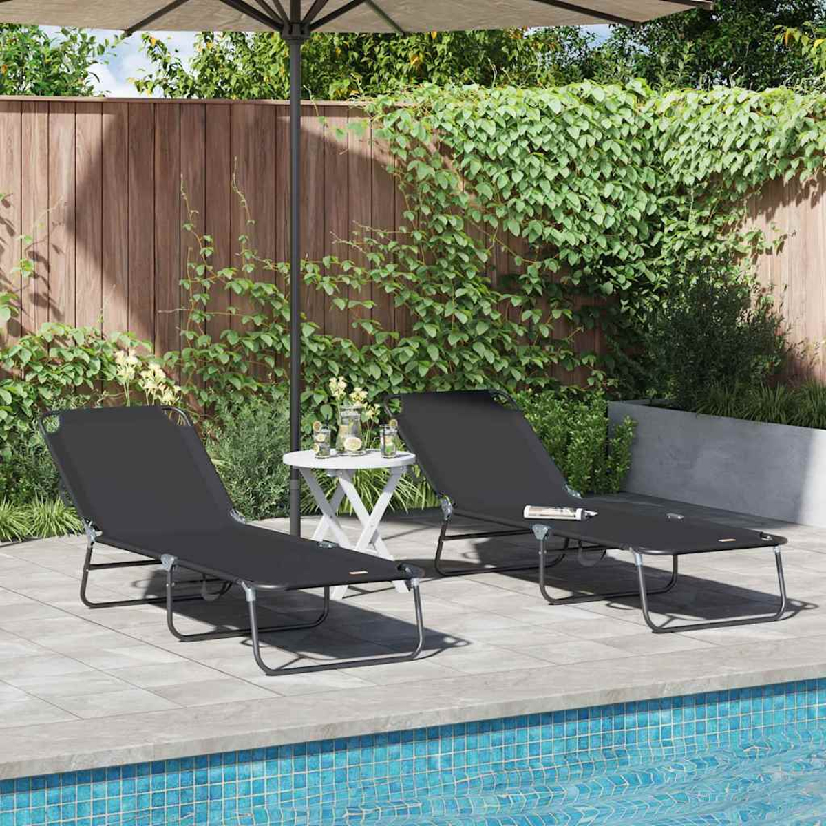 Zwei schwarze Liegestühle am Pool. Ein kleiner Tisch mit Getränken steht dazwischen. Hintergrund ist ein Holzzaun und Grün.