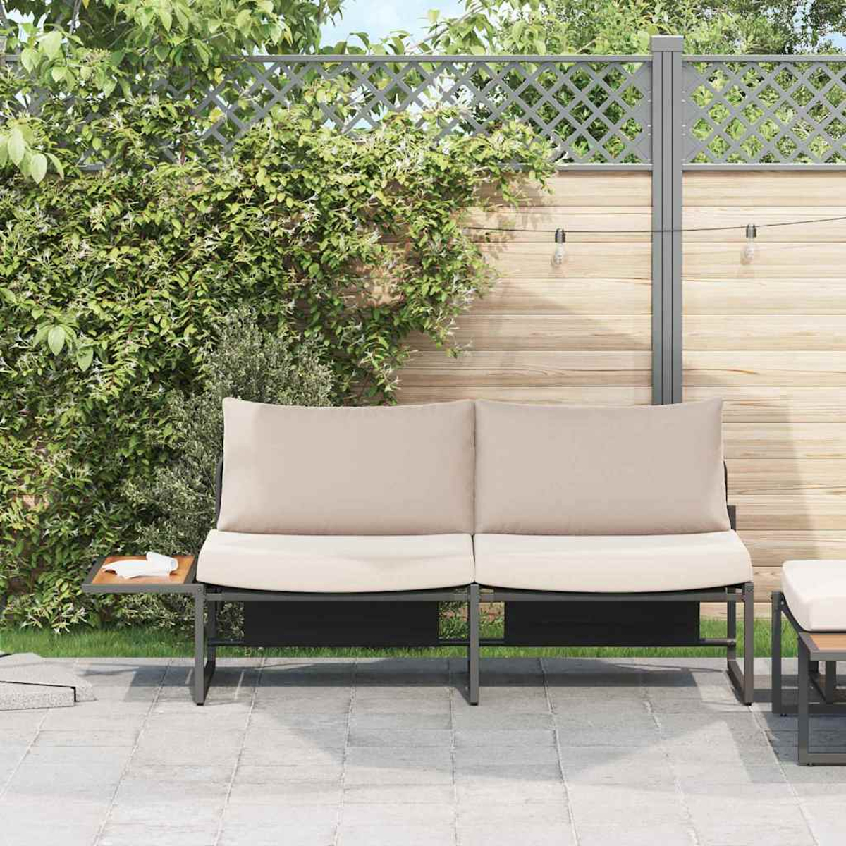 Outdoor-Sofa mit beigen Kissen auf einer Terrasse, umgeben von einem Holzzaun und grünem Laub. Auf der linken Seite befindet sich ein Beistelltisch.