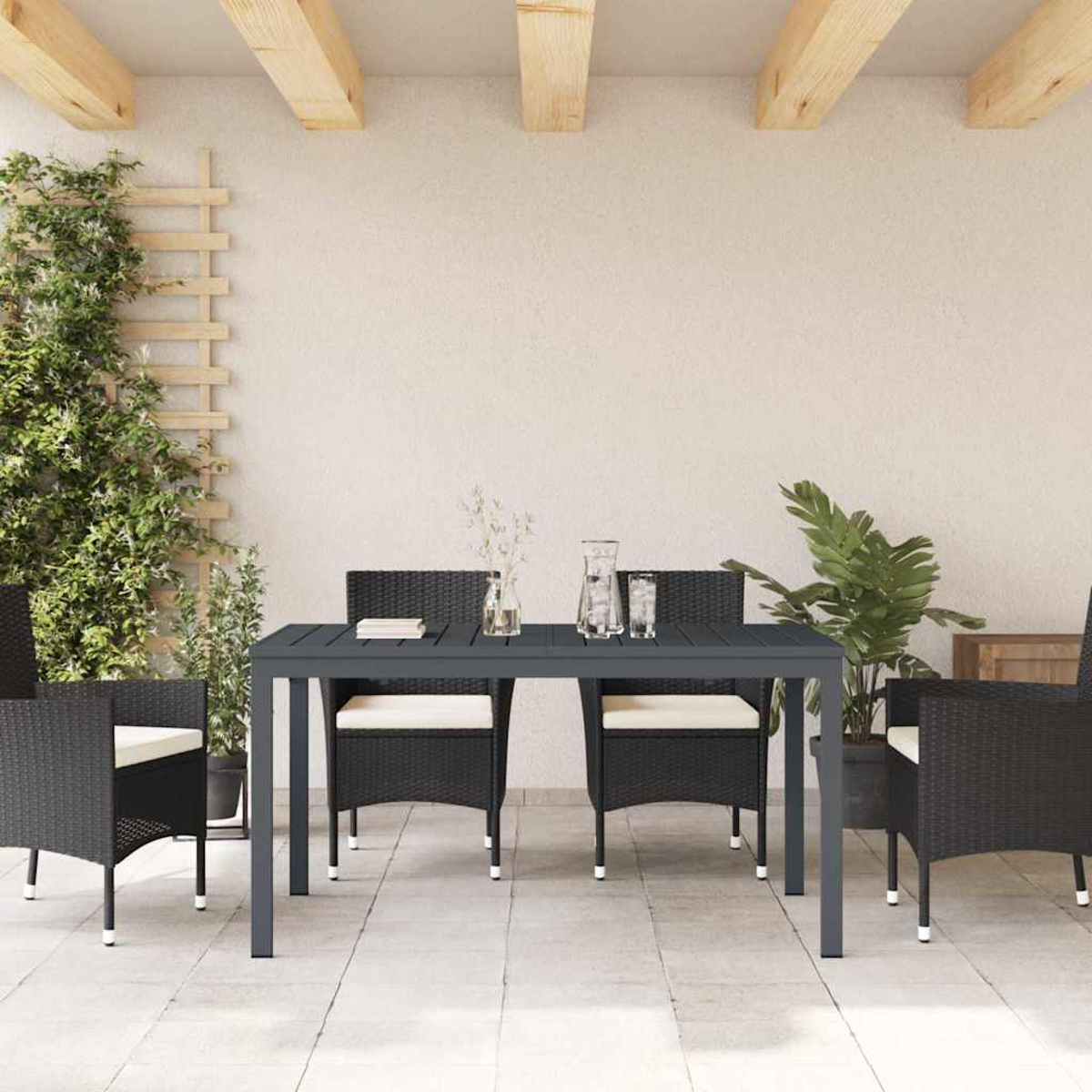 Terrassenset mit dunklem grauen Tisch und Stühlen. Links Pflanzen und ein Spalier. Auf dem Tisch eine Vase und Gläser.