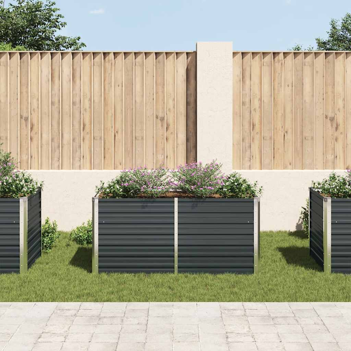 Drei dunkelgraue Metallpflanzkästen mit Pflanzen auf grünem Gras. Holzzaun und helle Wand im Hintergrund. Gepflasterter Boden davor.