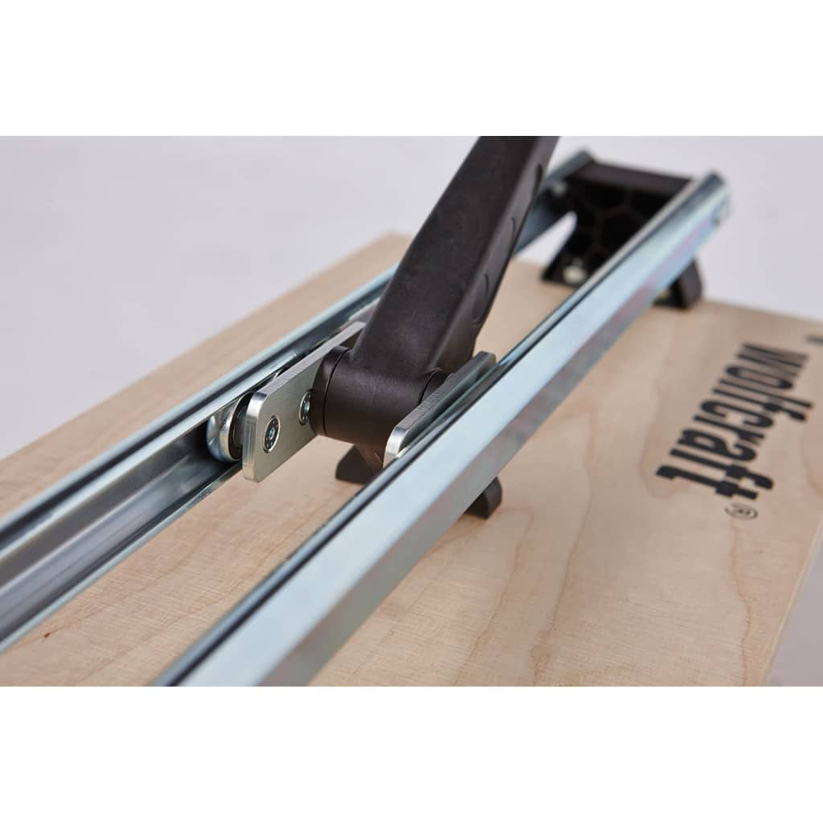 Strumento su base di legno. Binari metallici e manico nero. 'wolfcraft' è stampato sul legno.