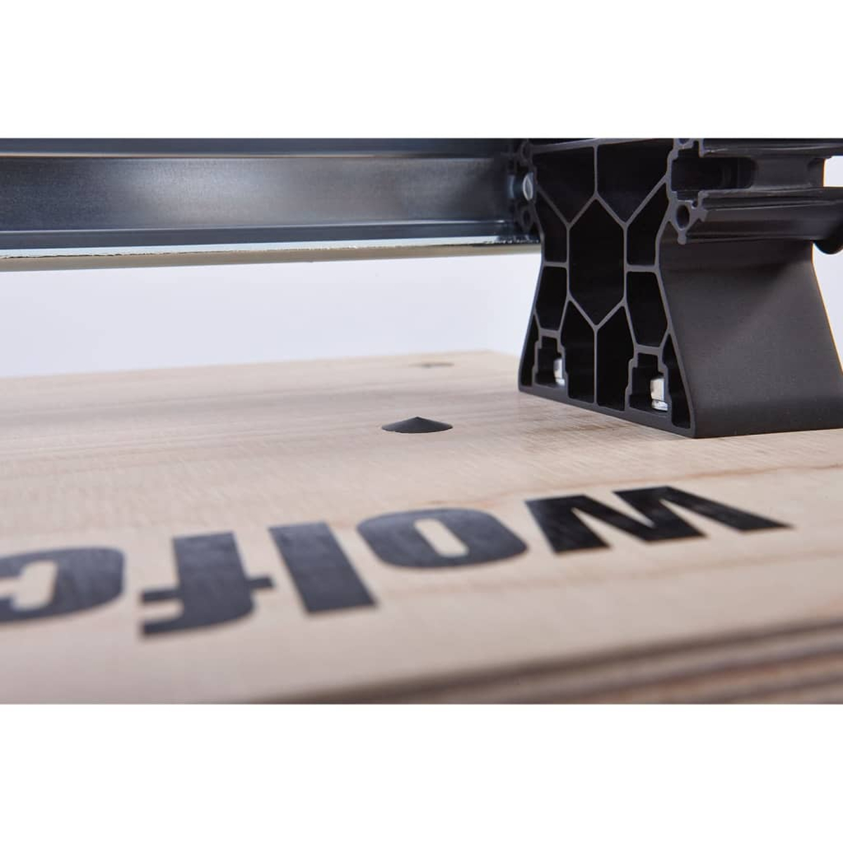 Primo piano di una superficie in legno con logo nero. Sono visibili una trave metallica e un supporto in plastica nera.