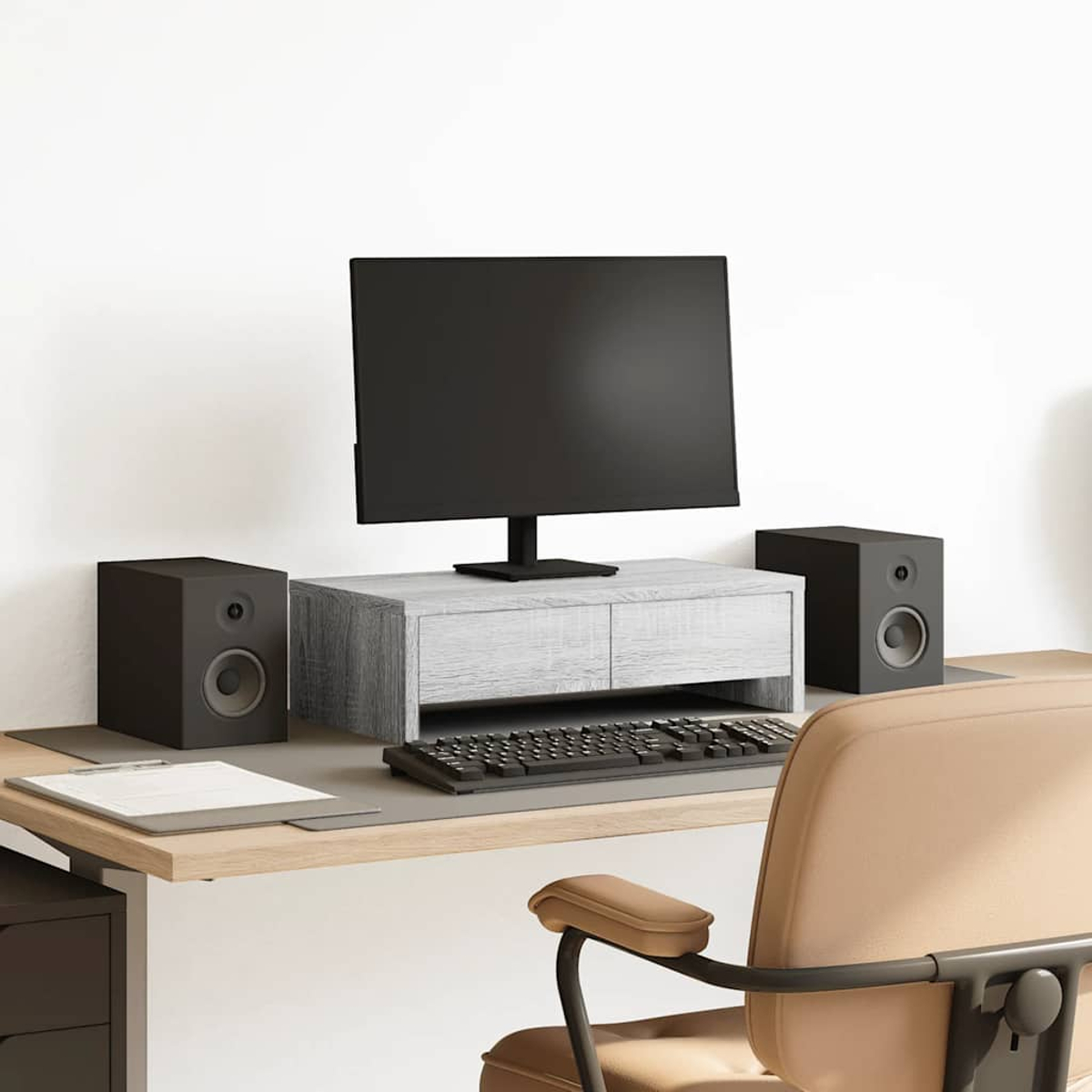 Ein Schreibtisch-Setup mit Computermonitor, Tastatur, Lautsprechern und einem Stuhl. Der Schreibtisch hat eine Holzoberfläche und ein graues Mauspad.