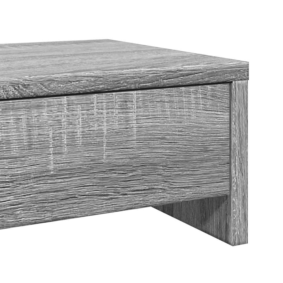 Nahaufnahme eines grauen Holzschranks. Sichtbar sind die Oberseite, eine Schubladenfront und ein Stützbein. Die Holzmaserung ist sichtbar.