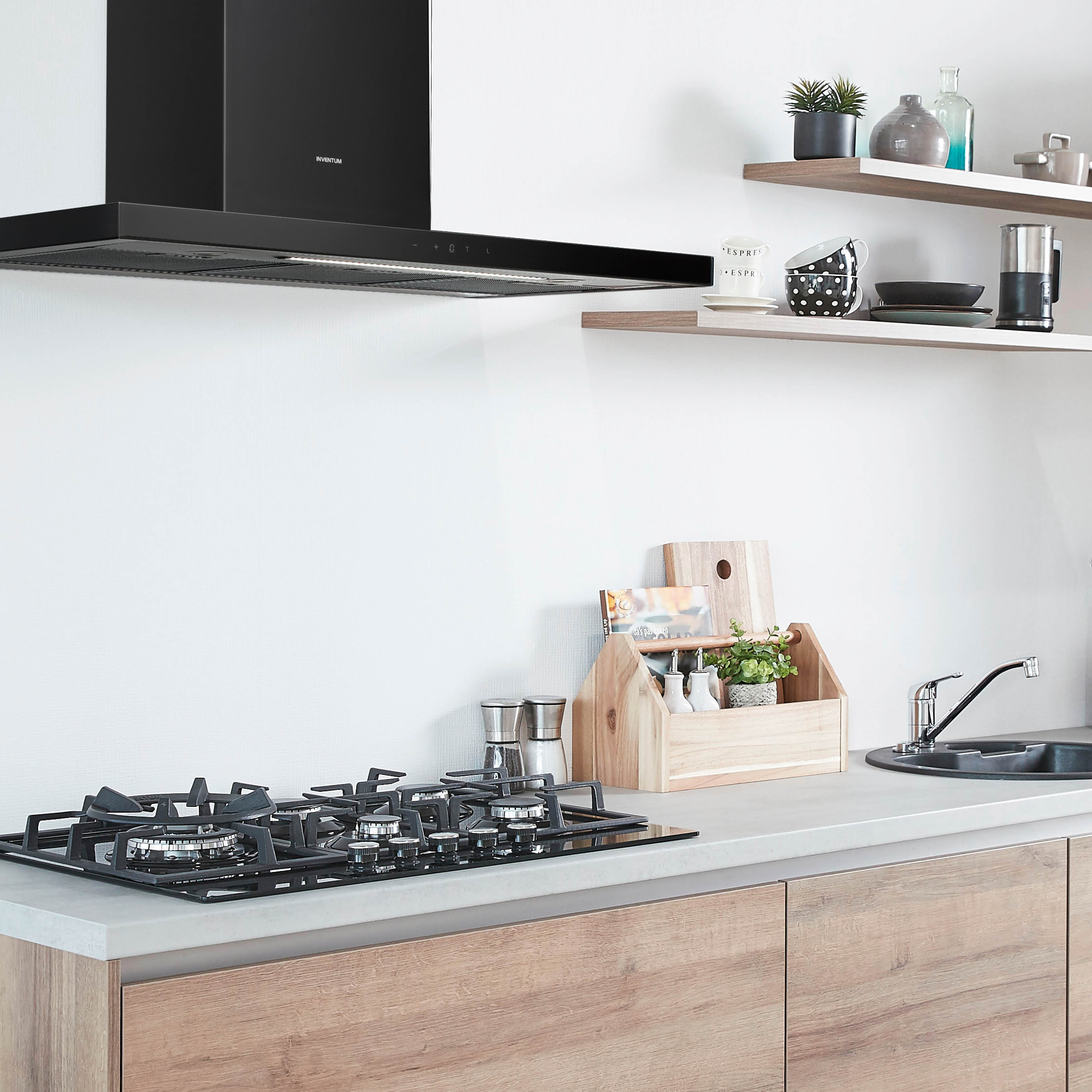 A kitchen with a black range hood, stove, wooden shelves, and cabinets. Various kitchen items are displayed.