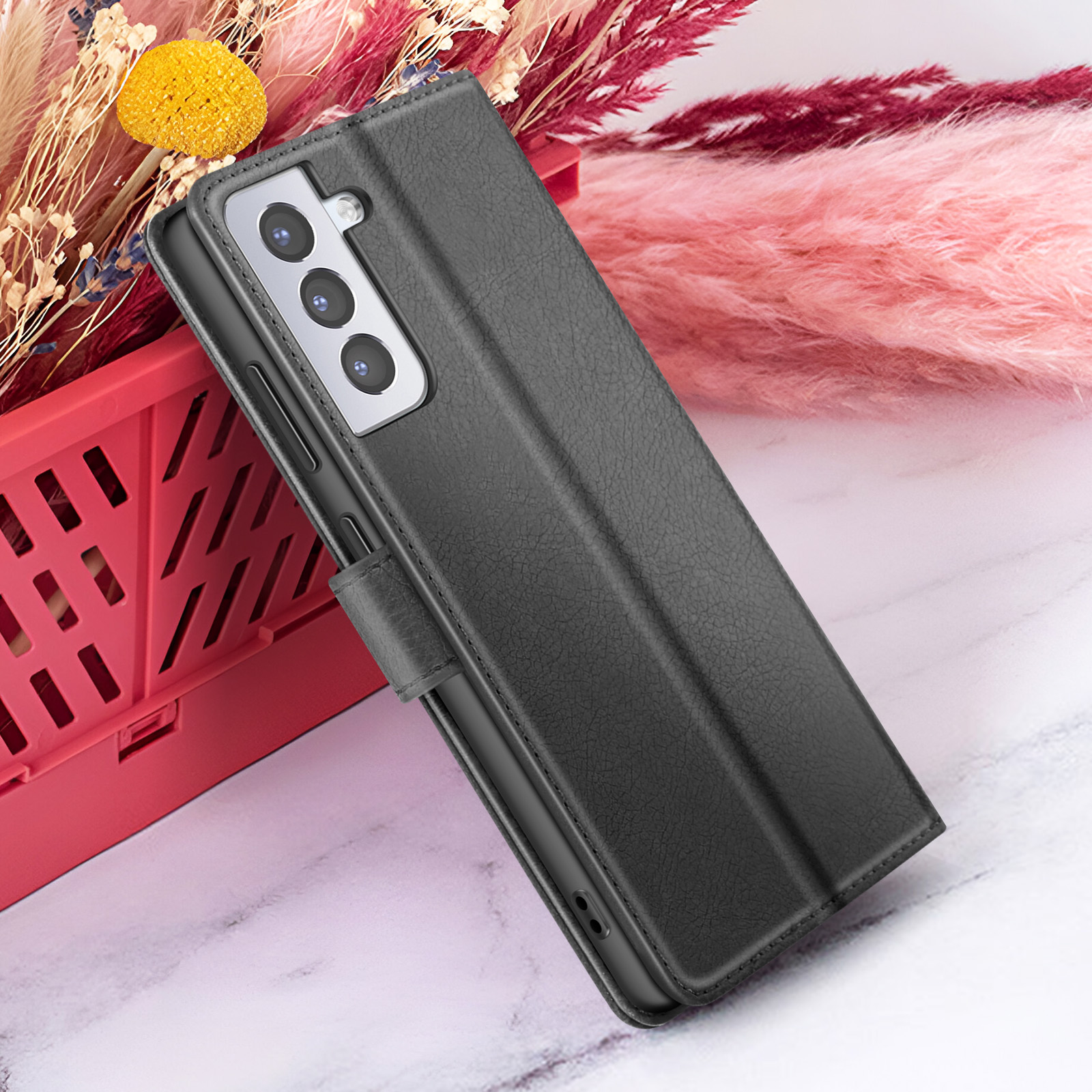 Étui de téléphone noir sur surface en marbre, fond floral rose et rouge, avec un panier rouge.