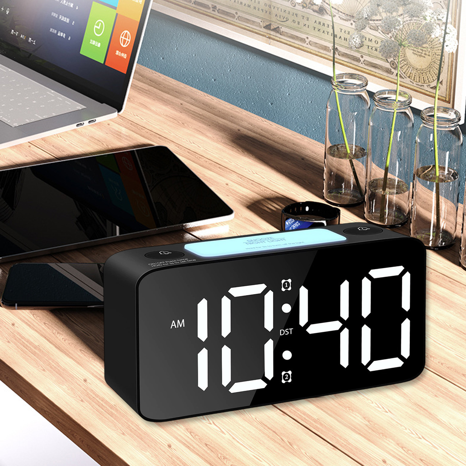 Eine Digitaluhr zeigt 10:40 Uhr an. Laptop, Tablet und Vasen sind in der Nähe. Der Hintergrund ist eine Wand und ein Holztisch.