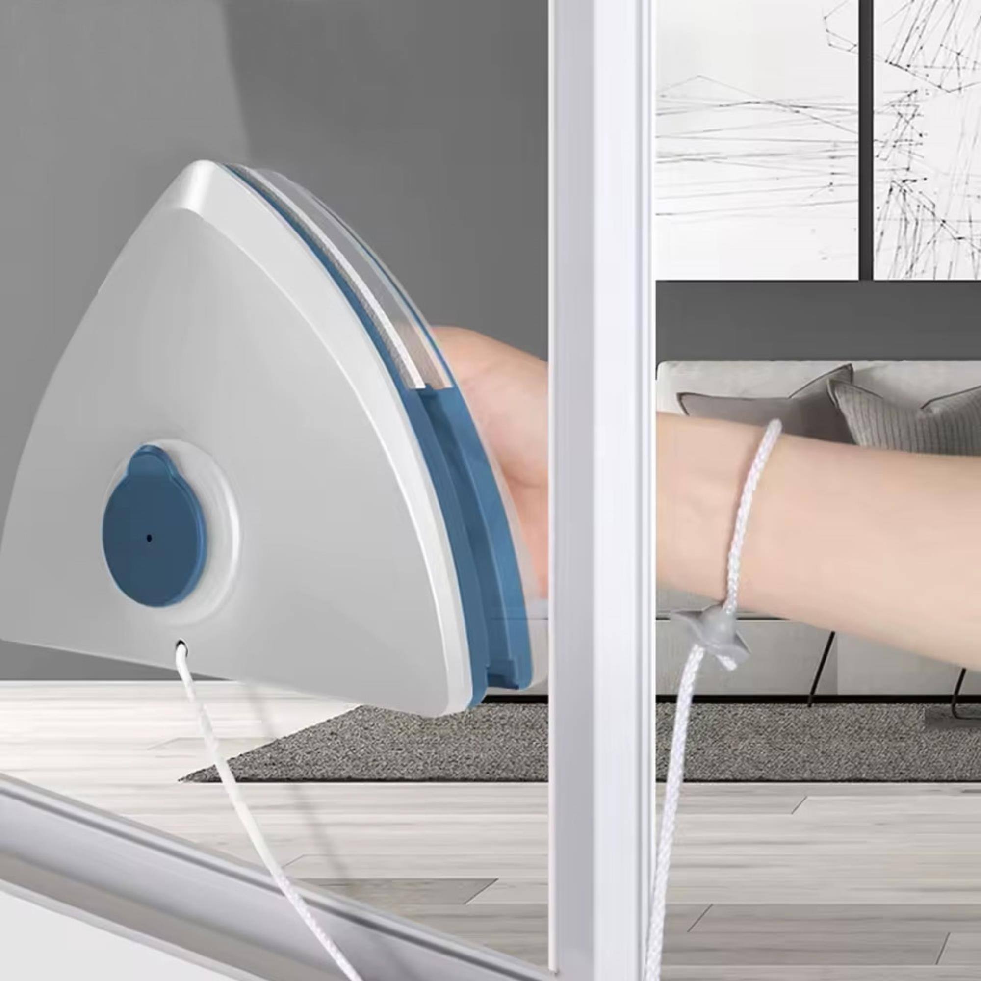 Una mano sostiene un limpiacristales blanco y azul. El fondo muestra una habitación con una pintura y una cama.
