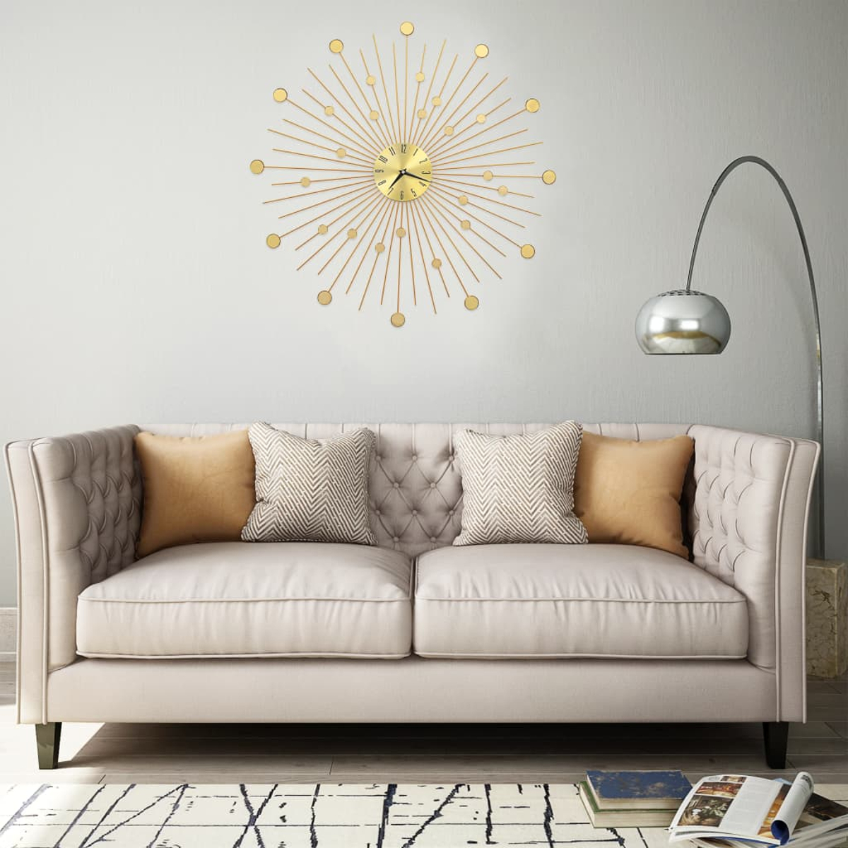 Wohnzimmerszene mit beigem Sofa, Zierkissen, goldener Uhr und silberner Stehlampe. Bücher und ein Teppich liegen auf dem Boden.