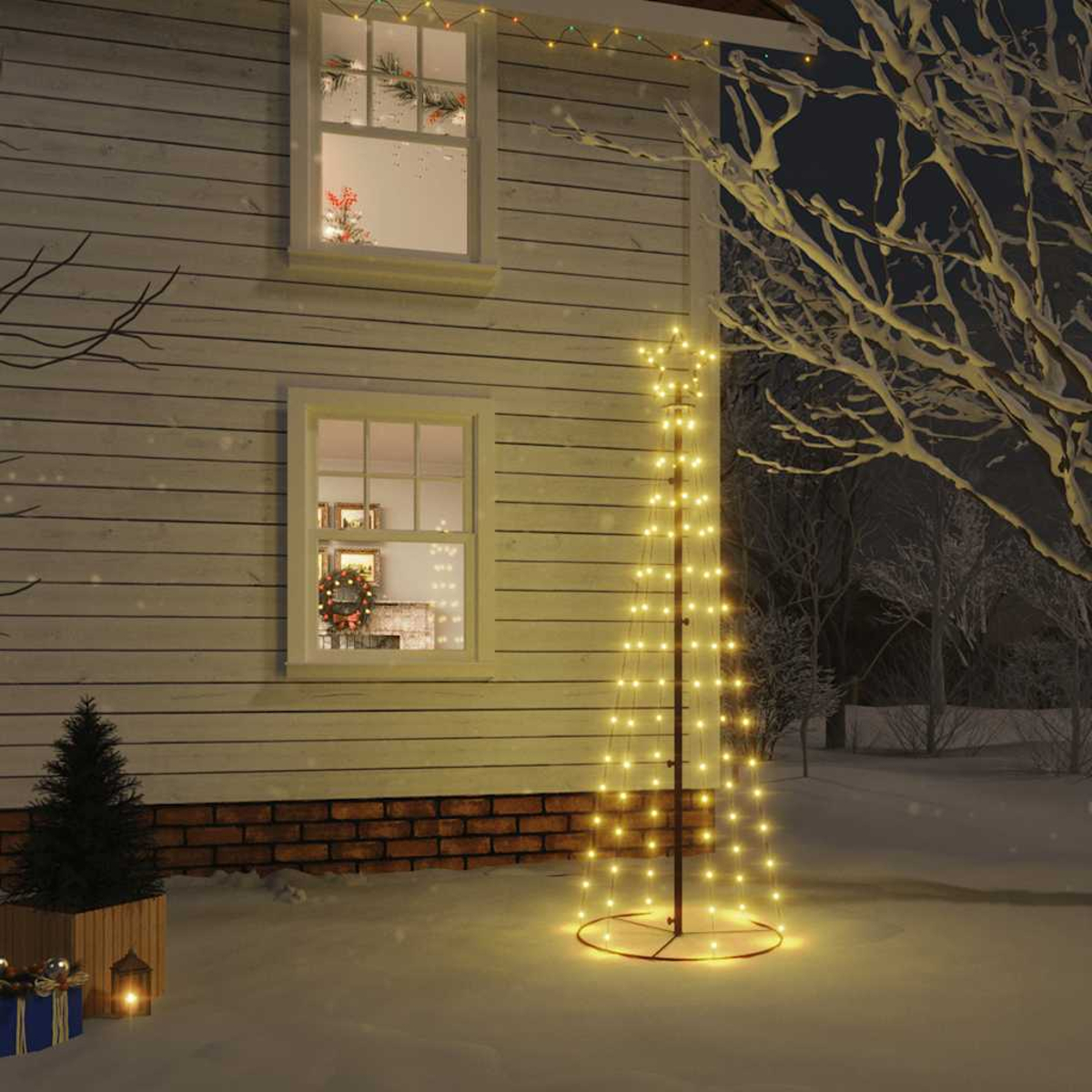Ein Haus bei Nacht mit einem beleuchteten Weihnachtsbaum davor. Schnee bedeckt den Boden. Fenster zeigen Weihnachtsdekorationen.